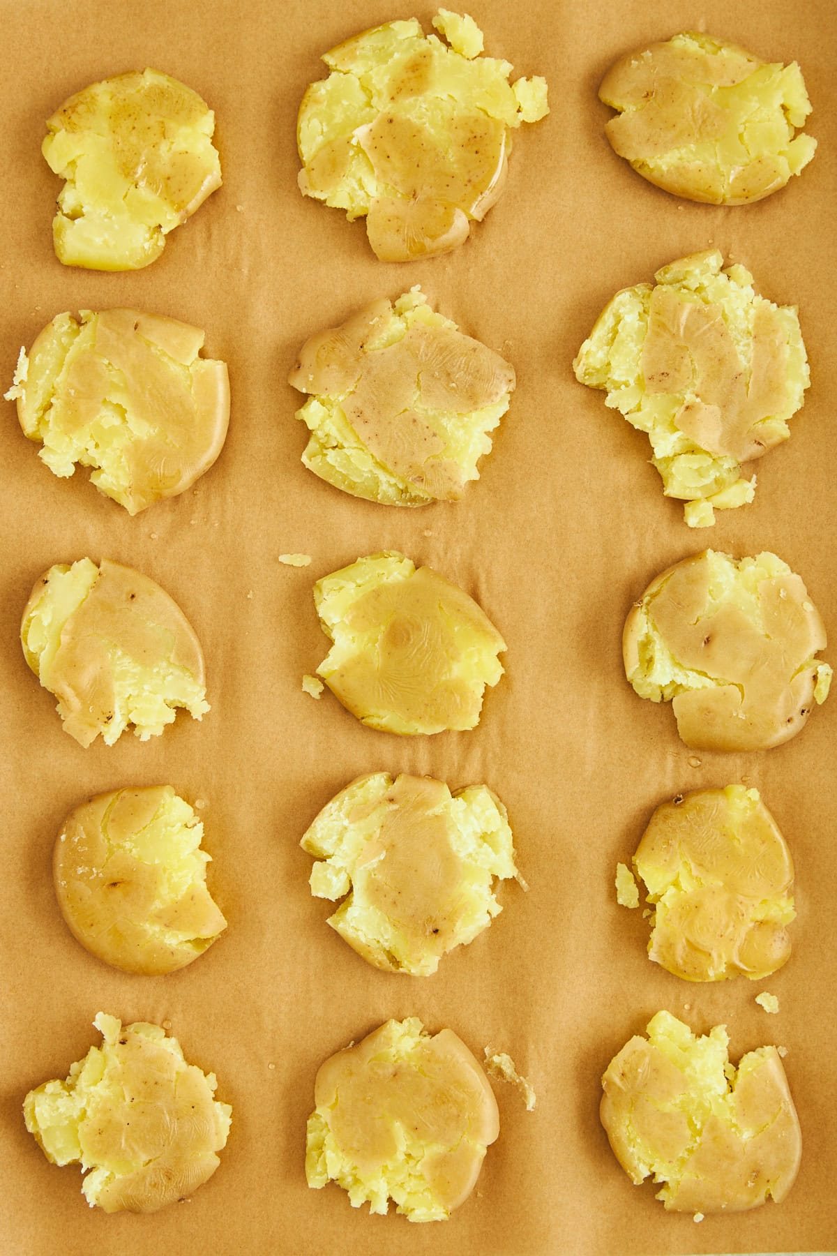 Boiled smashed potatoes on a parchment-lined baking sheet.