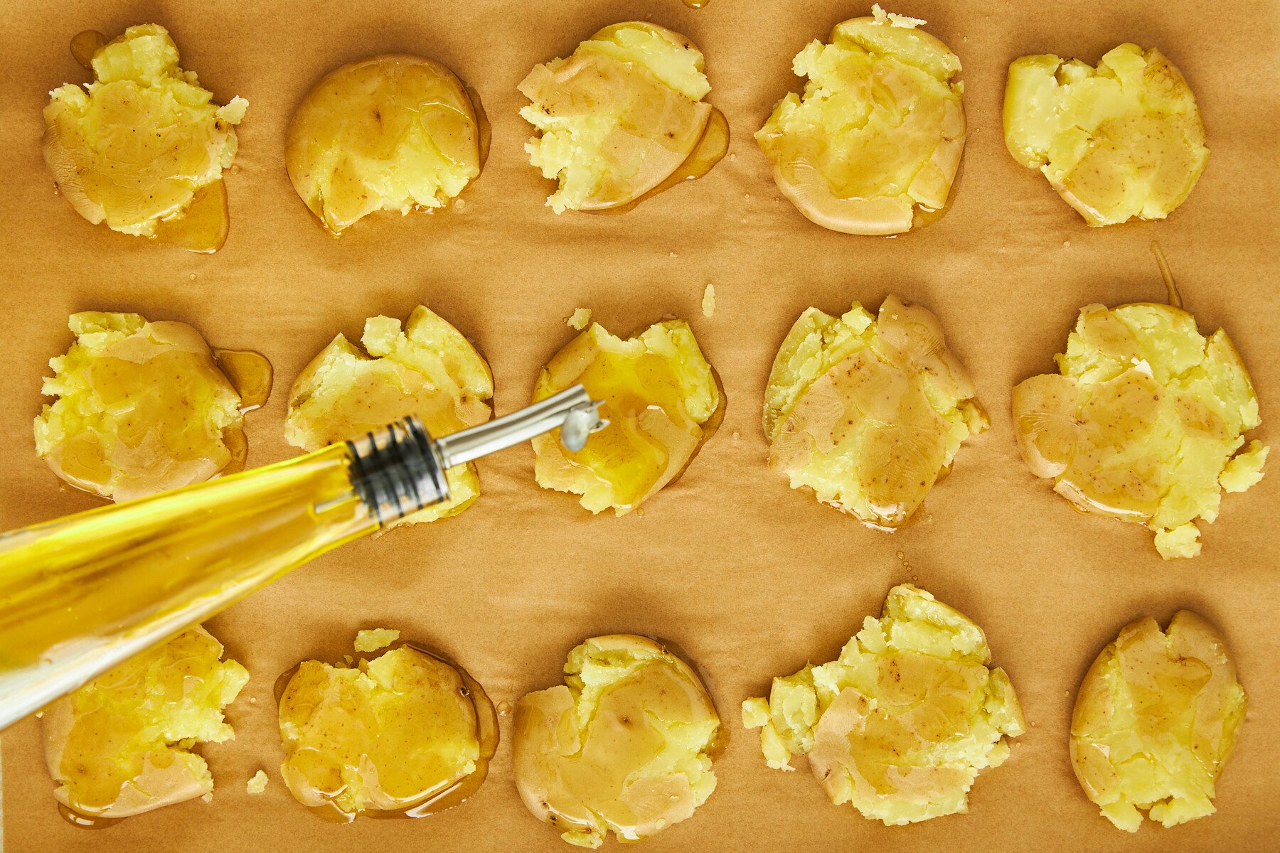 Boiled potatoes being topped with olive oil.
