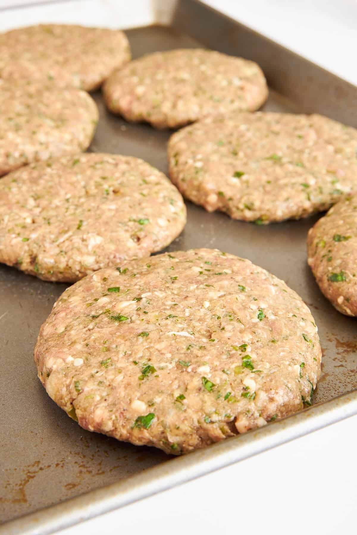 Lamb kofta burger patties on a baking sheet.