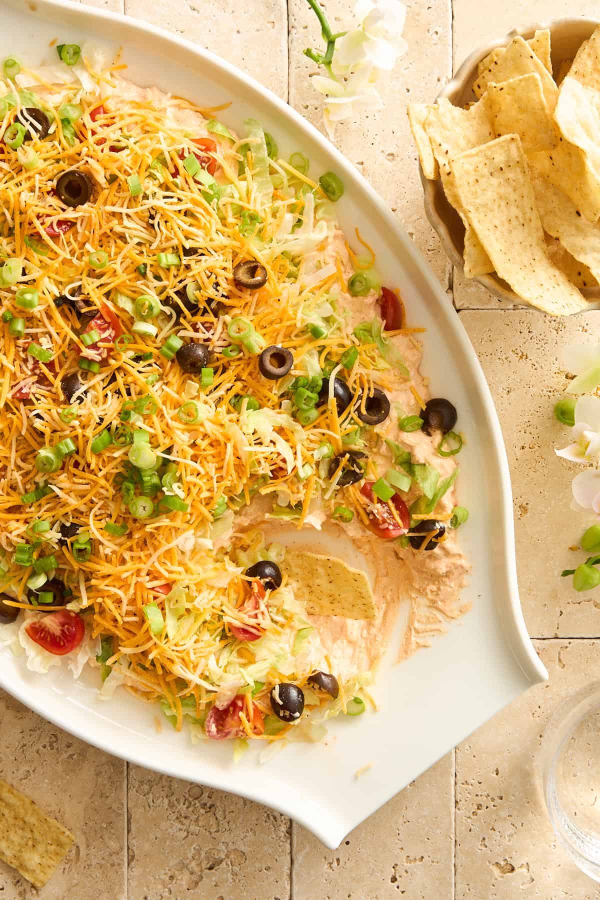 A platter of taco dip with scoops missing.