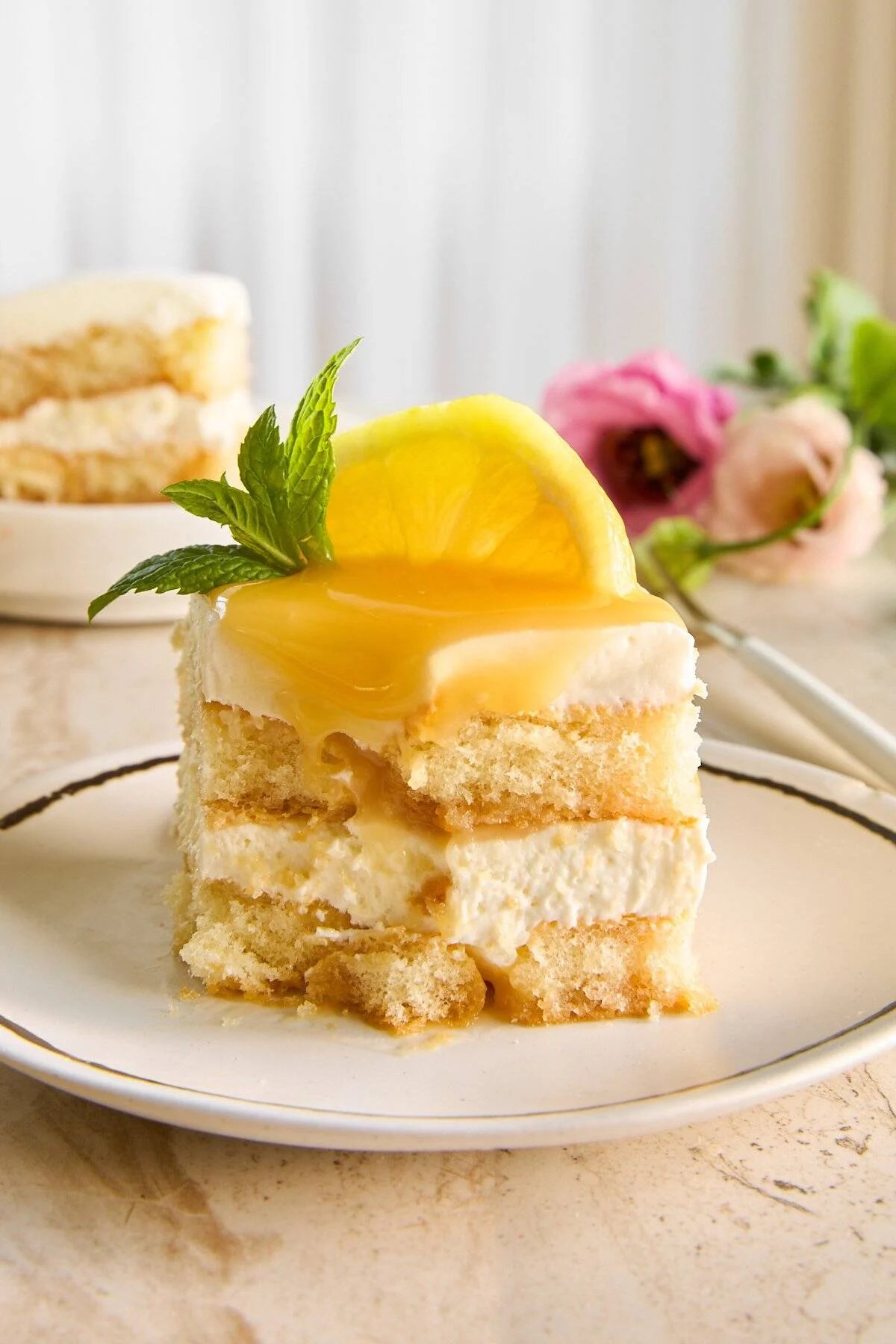 A slice of lemon tiramisu with lemon curd on a plate missing a bite.