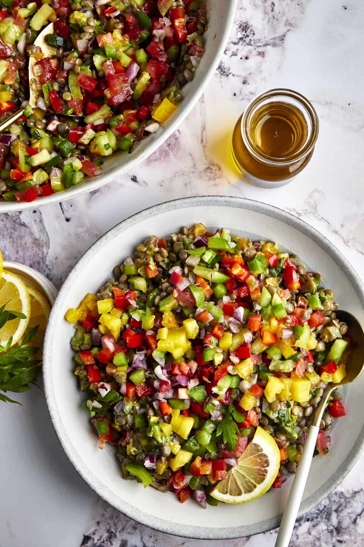 Overhead image of a bowl of lentil mango salad with a spoon on the side.