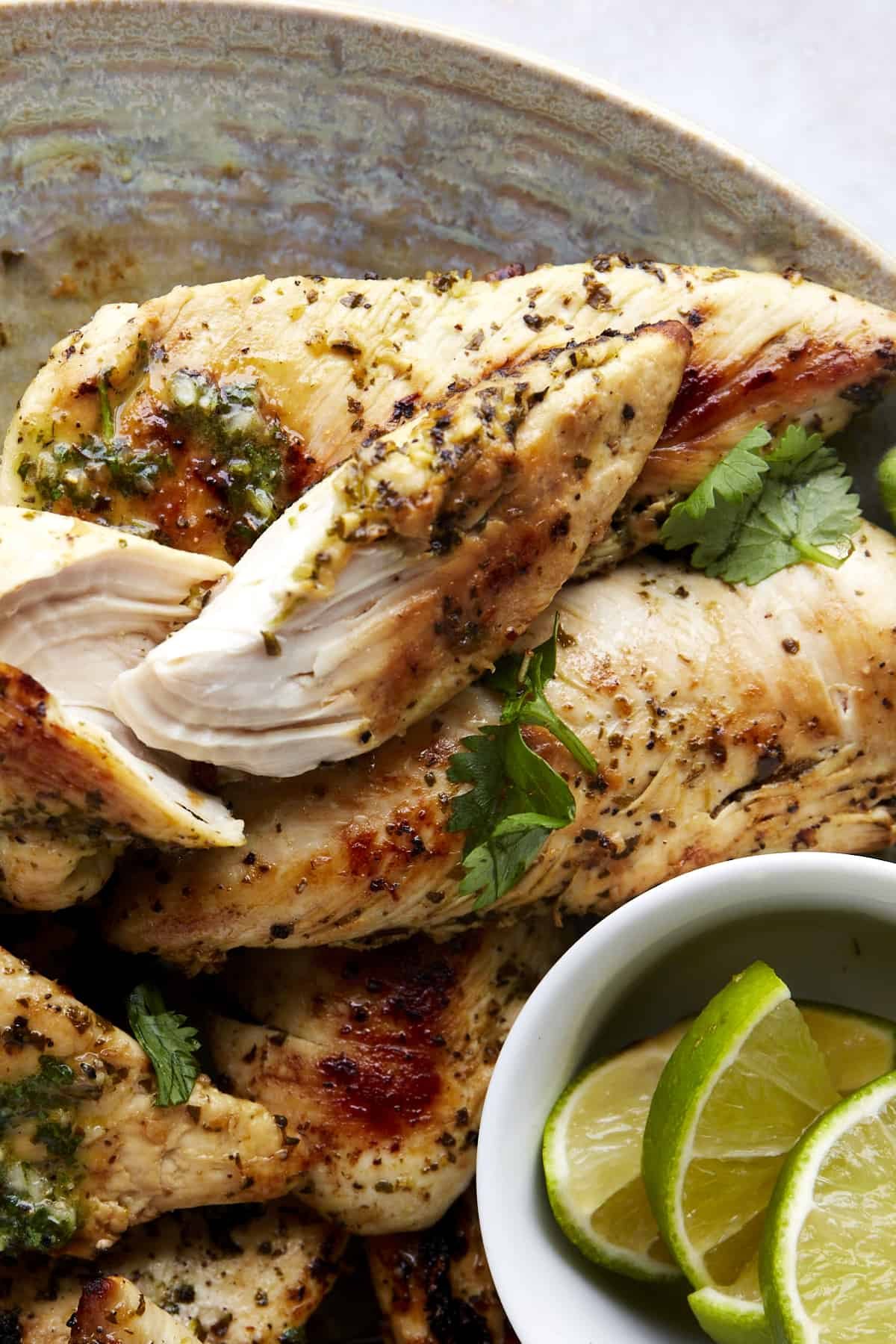 A basket of air fryer lime chicken with a bowl of lime wedges.