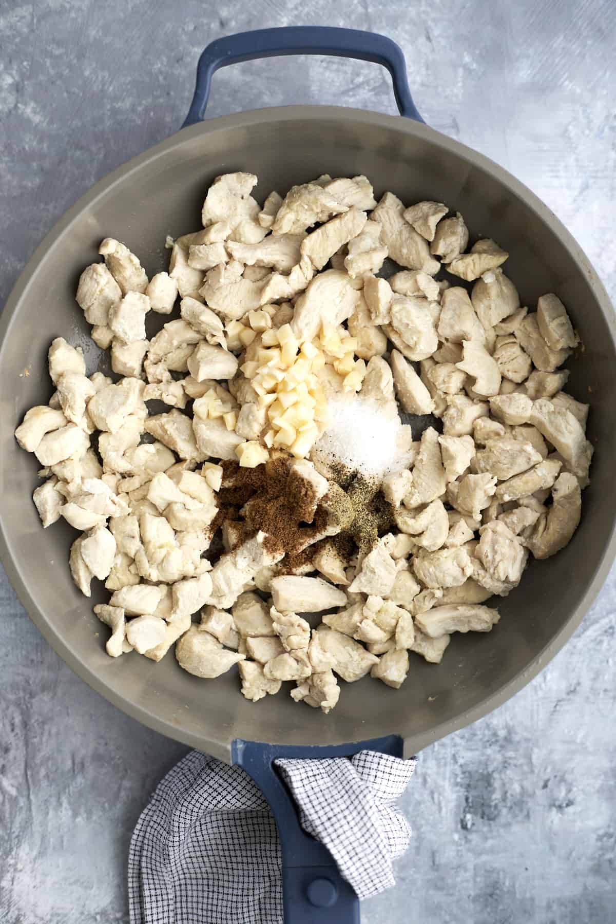 chicken pieces in a skillet topped with spices