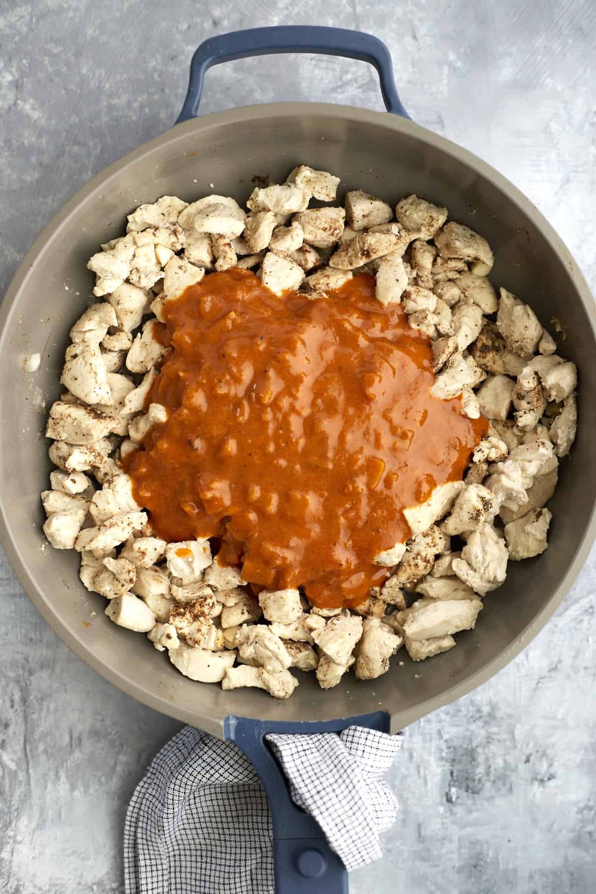 chicken pieces in a skillet topped with curry sauce