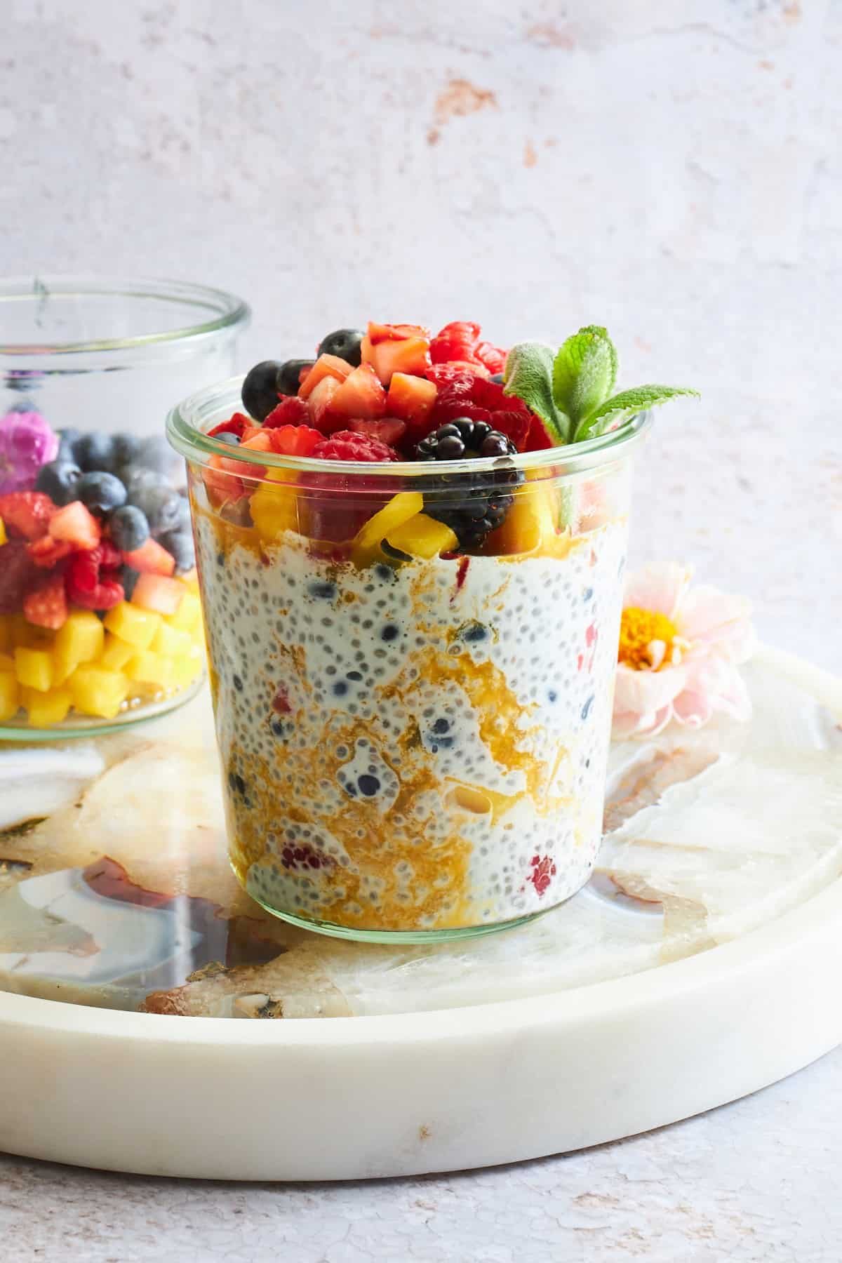 A jar of mango chia pudding topped with fruit salad.