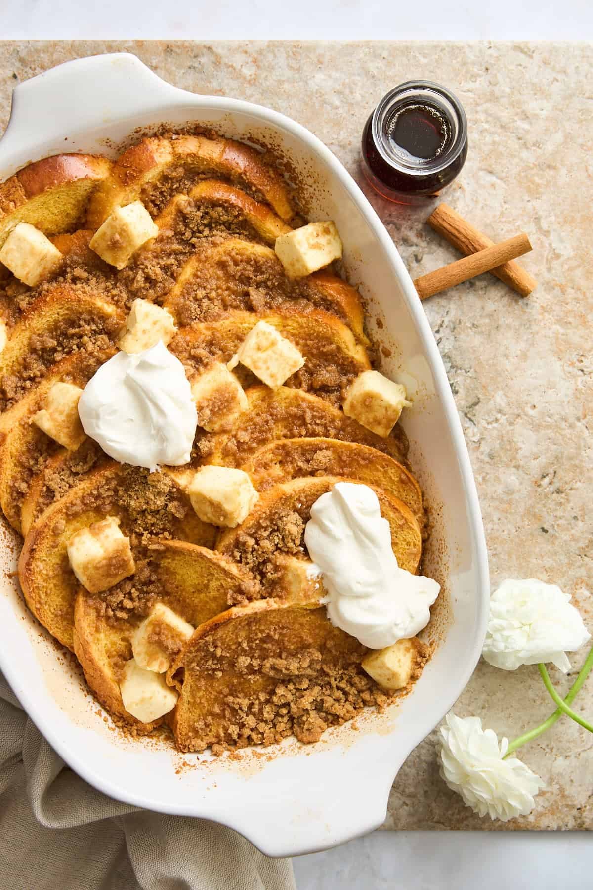 A baking dish of maple french toast topped with cream cheese and yogurt.
