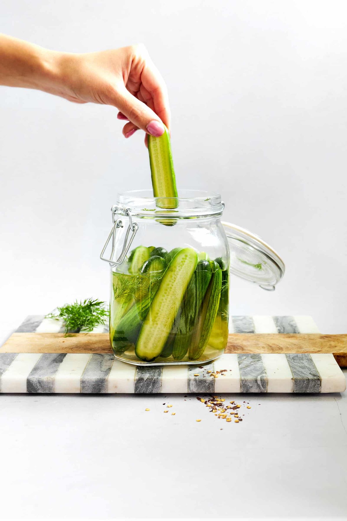 A marinated cucumber being pulled from a jar.