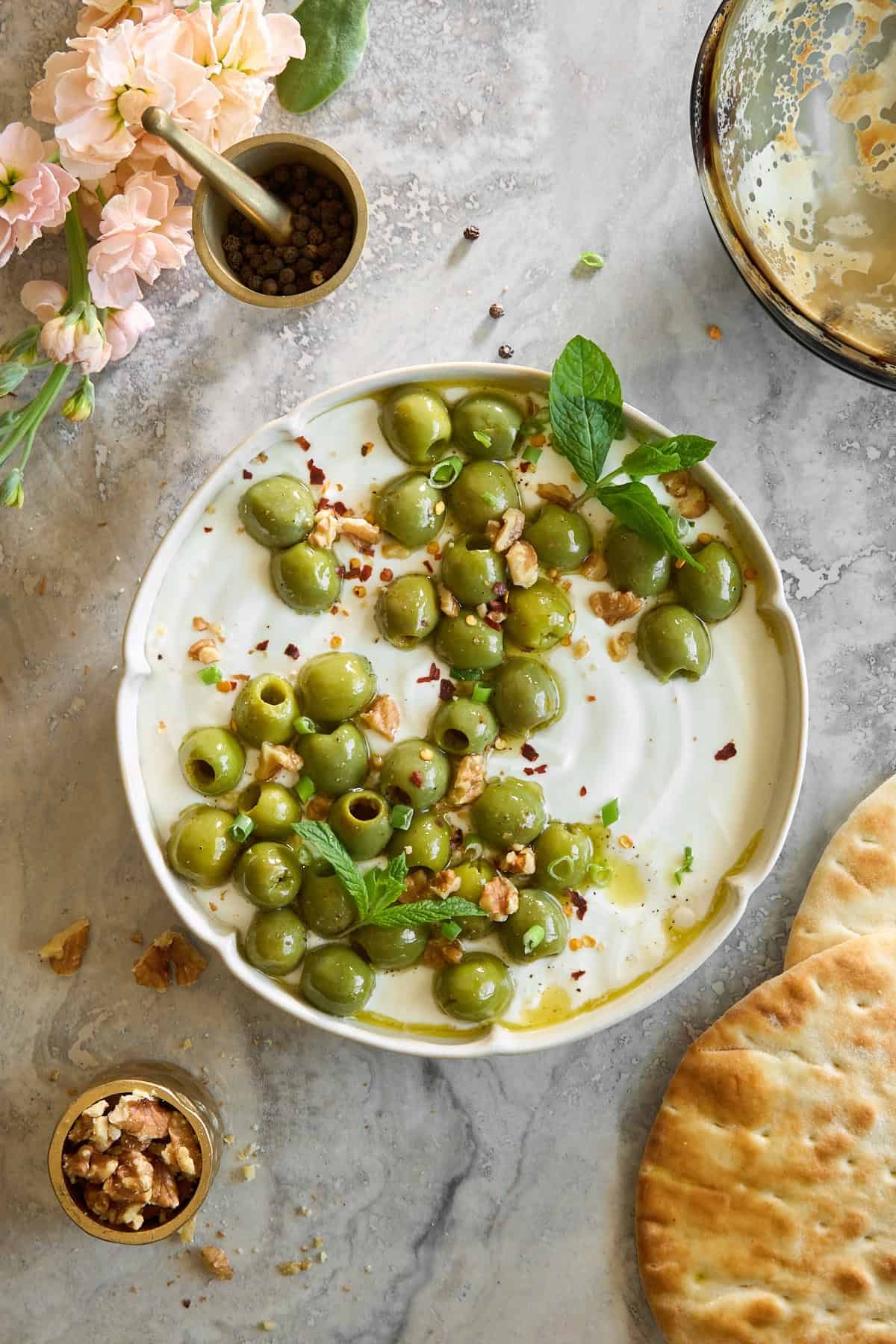 A bowl of whipped cottage cheese topped with marinated olives.
