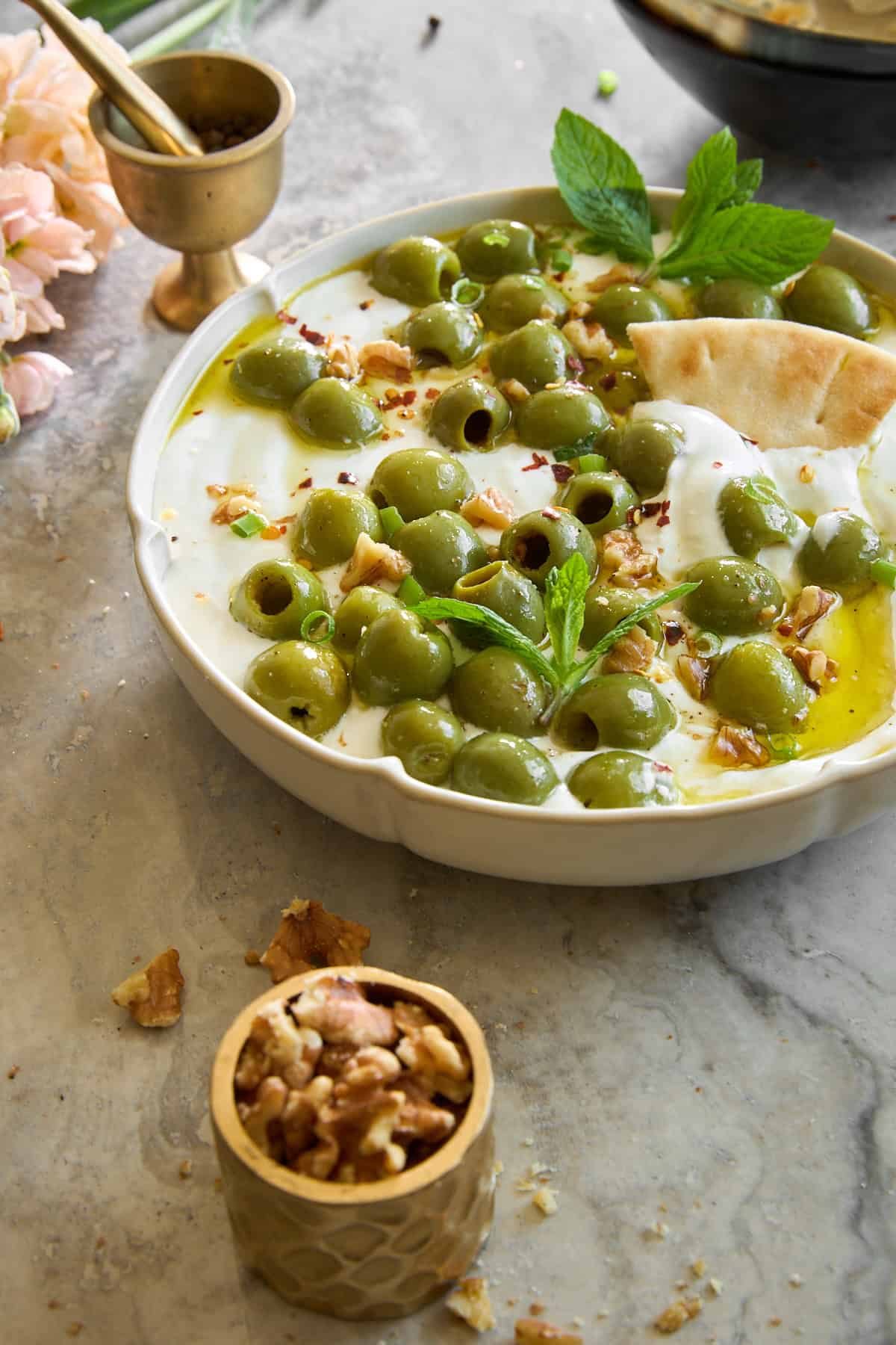 Marinated olive dip with whipped cottage cheese with a pita chip sticking out.
