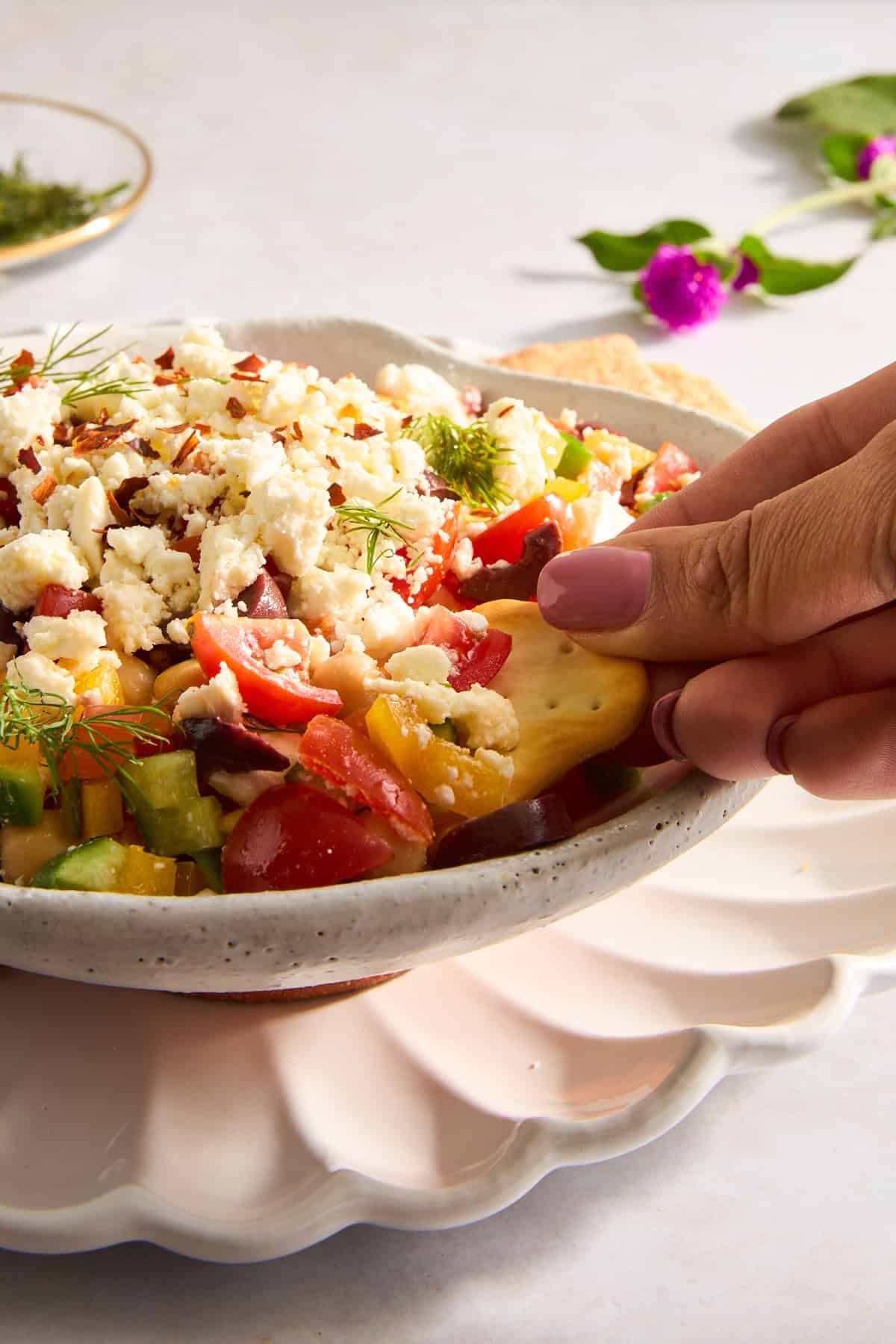 A pita chip being dipped into a bowl of Mediterranean feta dip.