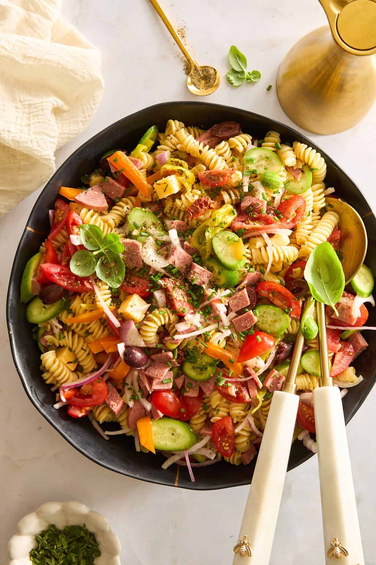 A bowl of Mediterranean pasta salad topped with fresh herbs.