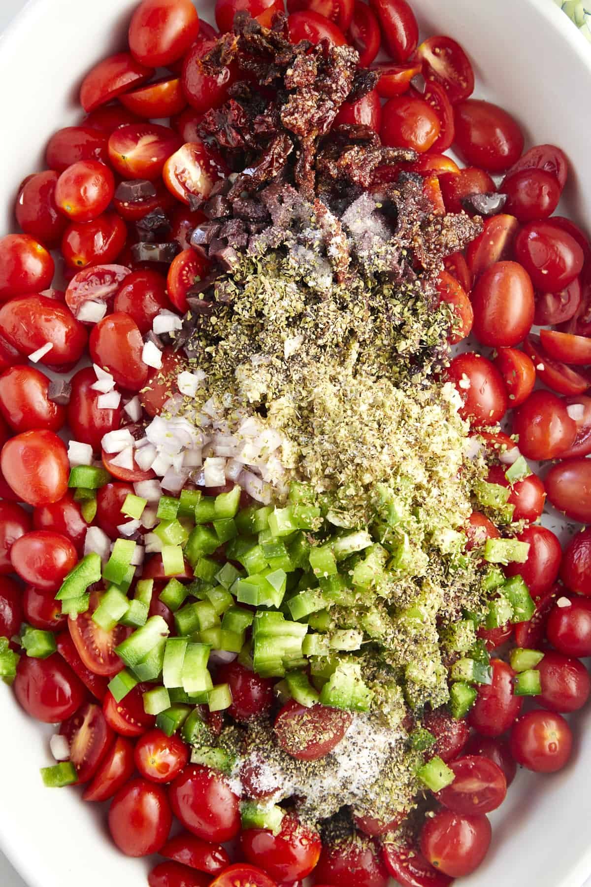 A baking dish with tomatoes, olives, bell pepper, onion, garlic, and seasonings.
