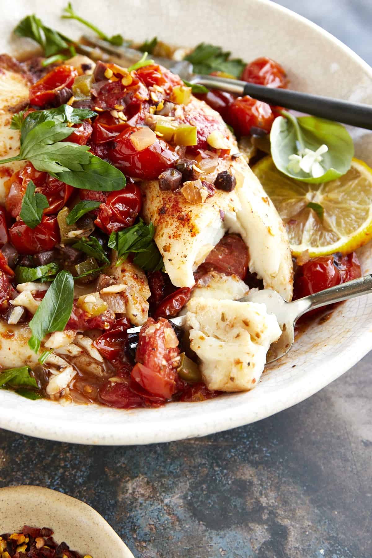 A fork taking a bite of Mediterranean tilapia.