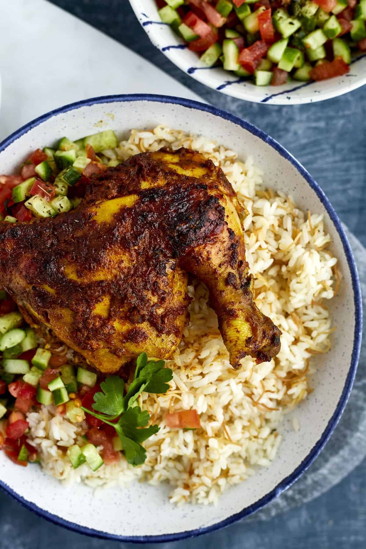 Middle Eastern chicken over vermicelli rice with tomato and cucumber salad on the side