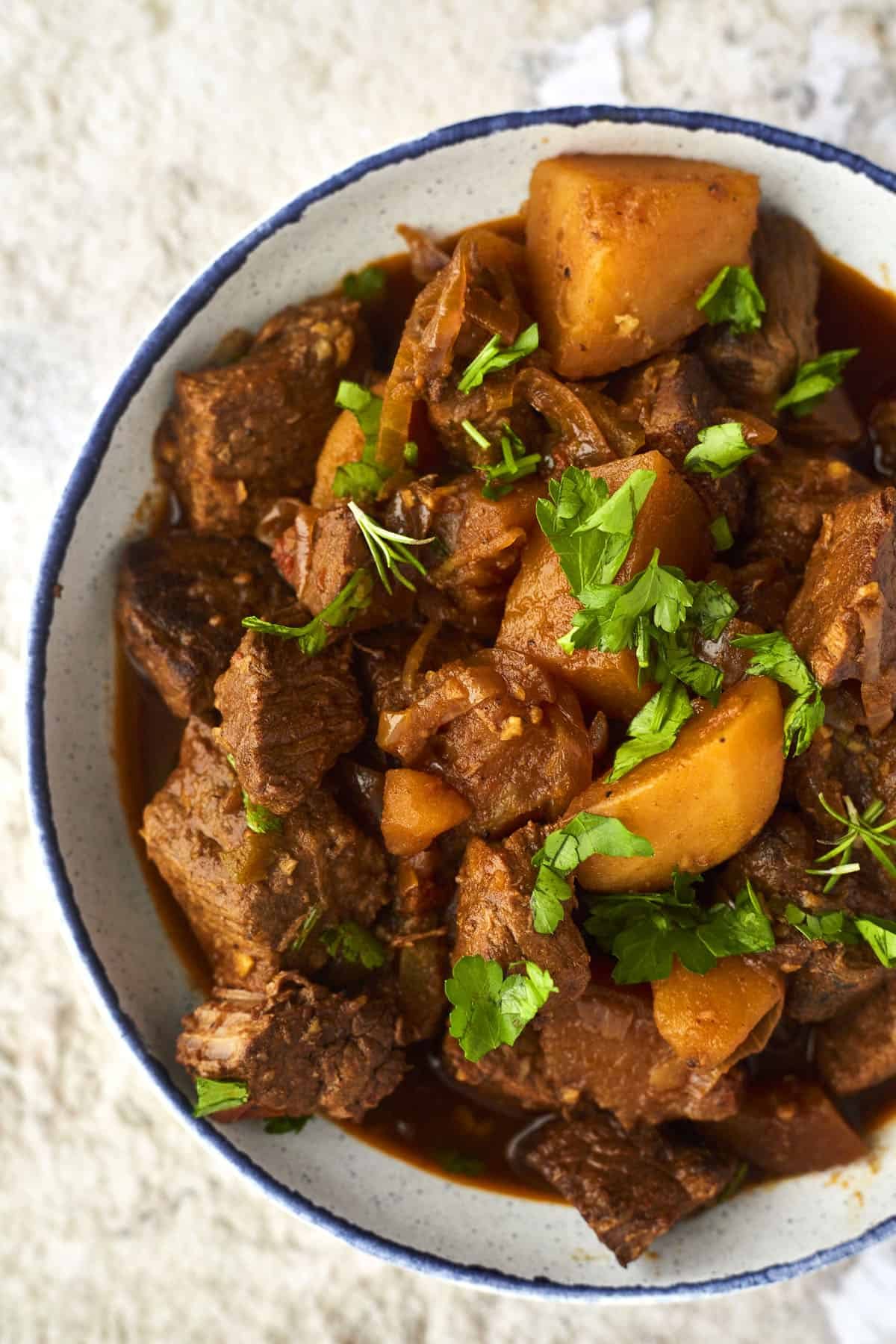 A bowl of Middle Eastern beef stew topped with fresh herbs.