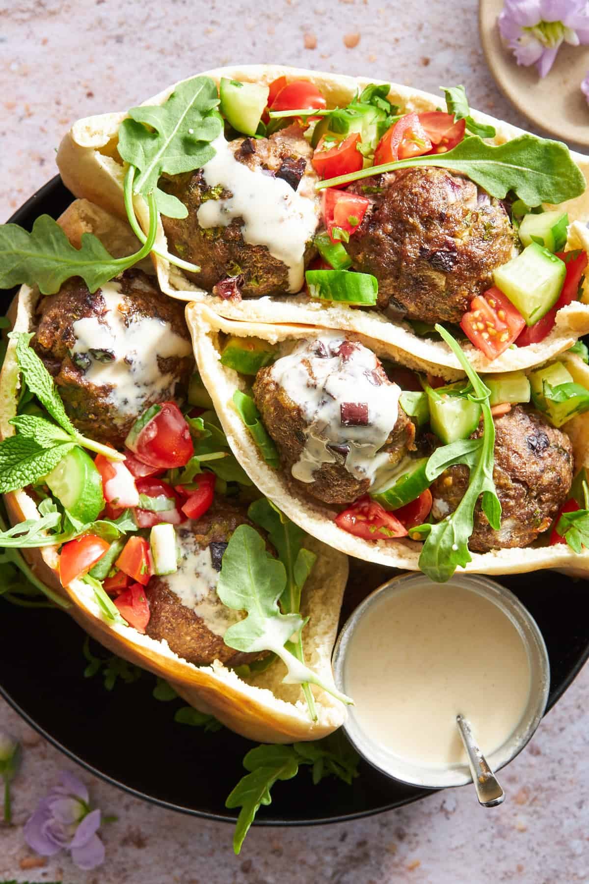 Pita pockets stuffed with tomato and cucumber salad, beef meatballs, and tzatziki.