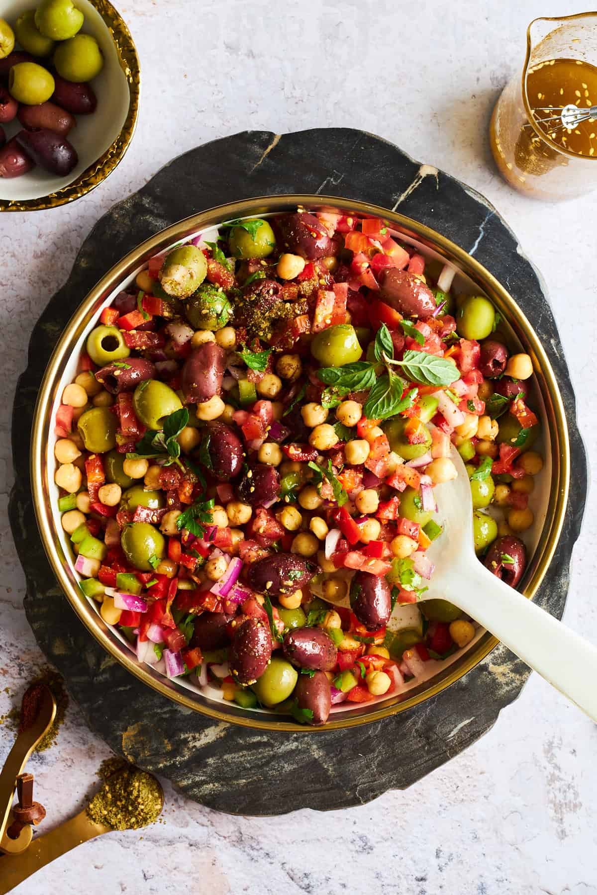 A bowl of olive salad with a spoon sticking out.