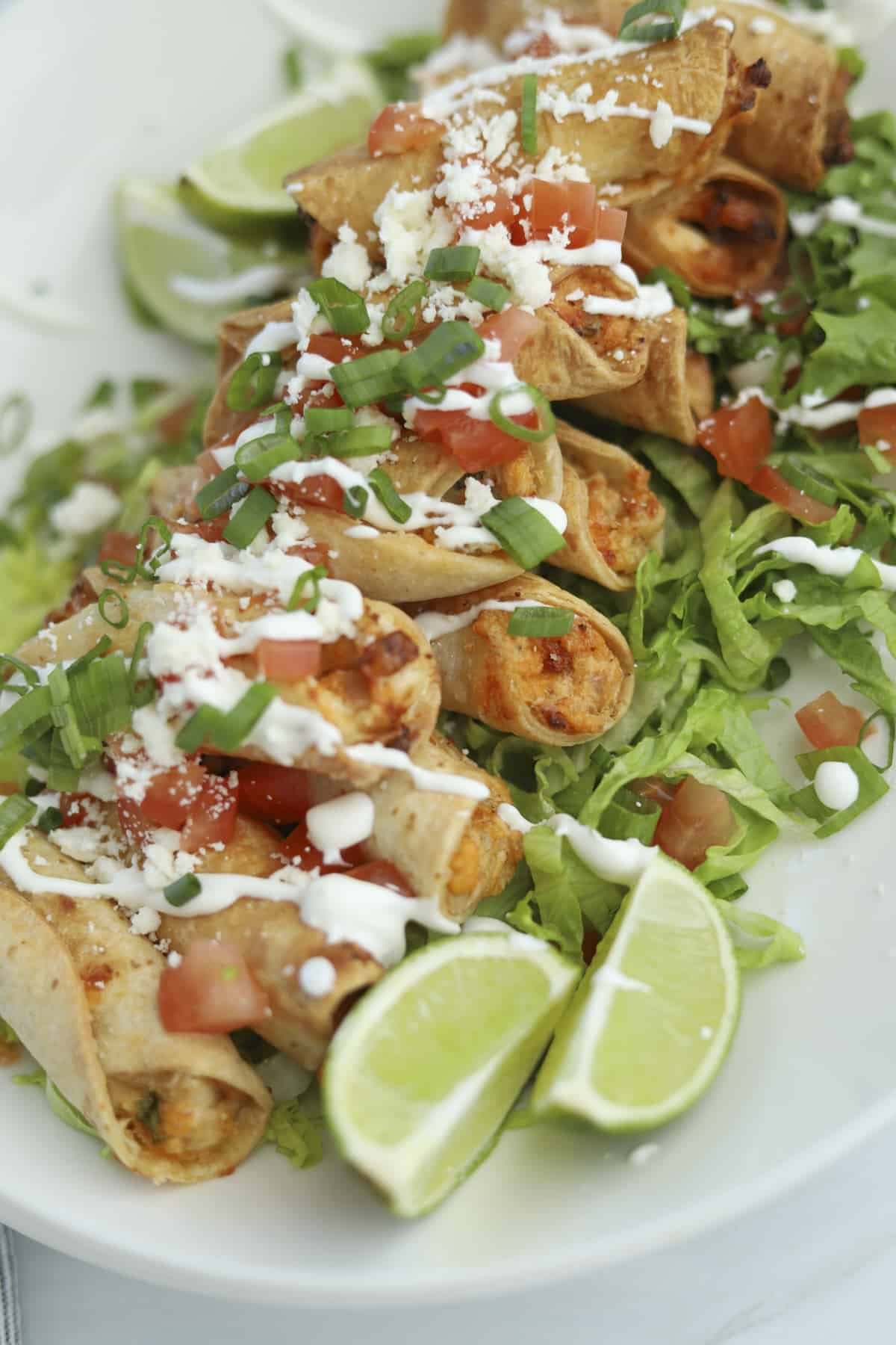 overhead of mini air fryer taquitos with tomatoes, sour cream, and green onions