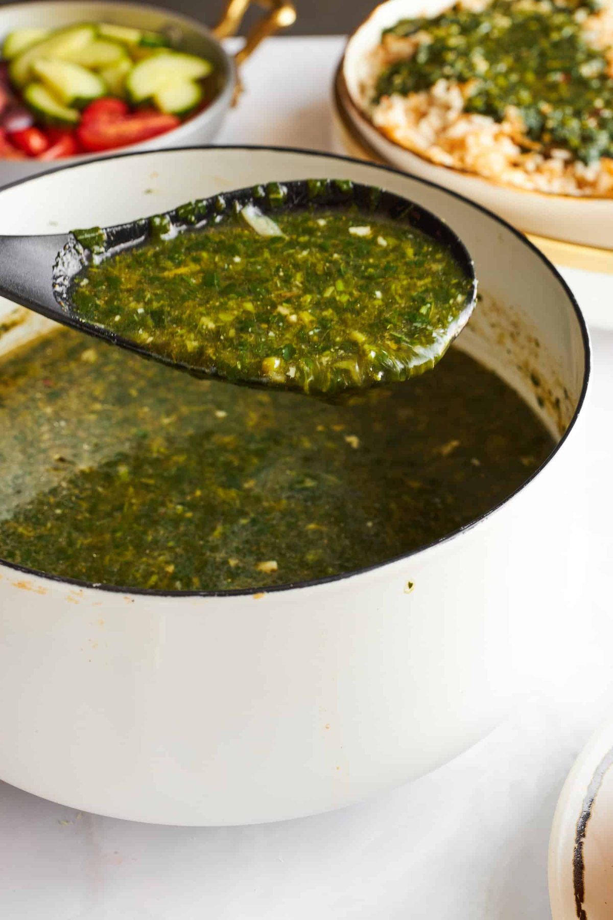 A spoon lifting a scoop of molokhia from a pot.
