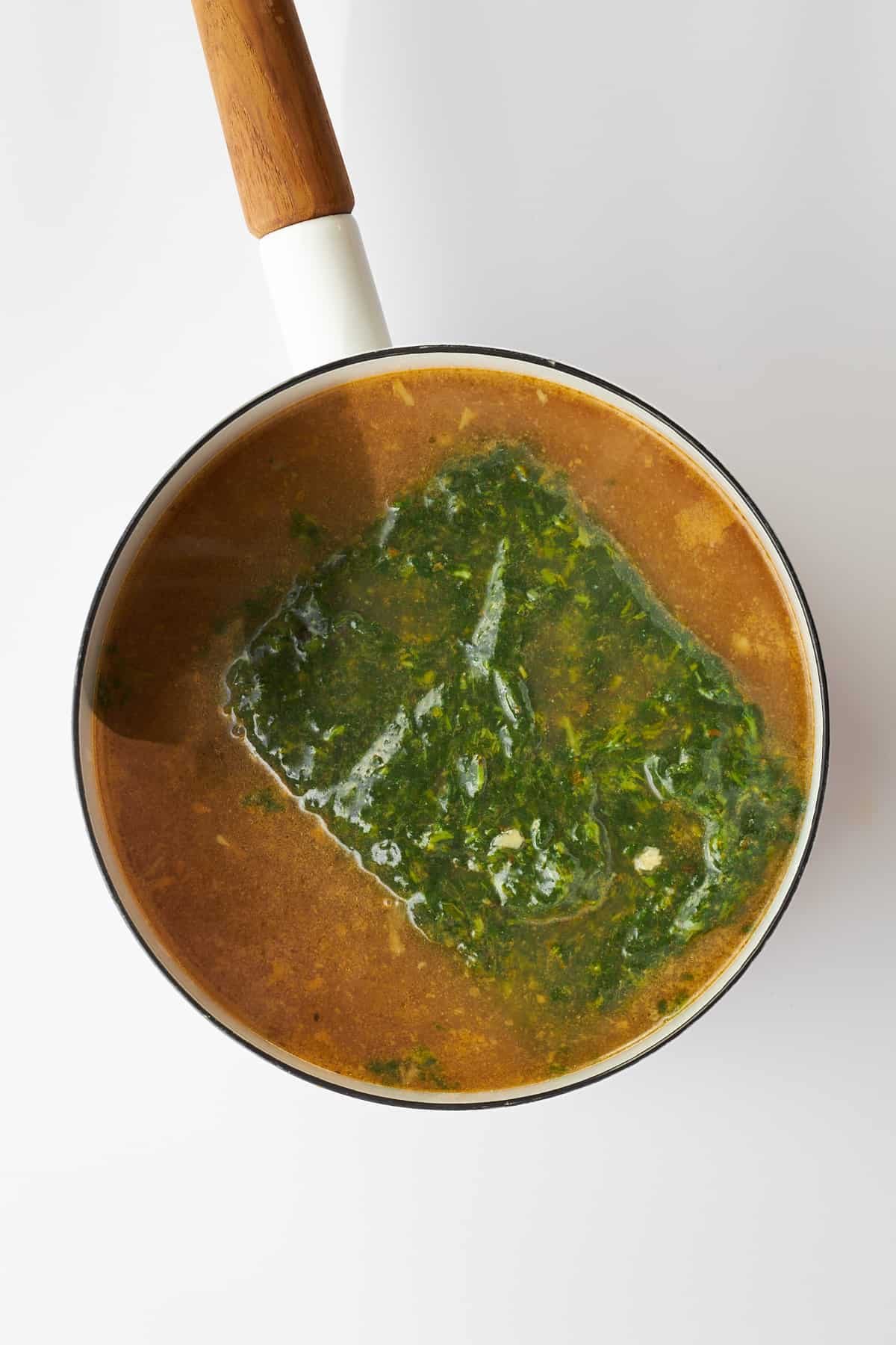 Molokhia leaves cooking in a pot with broth.