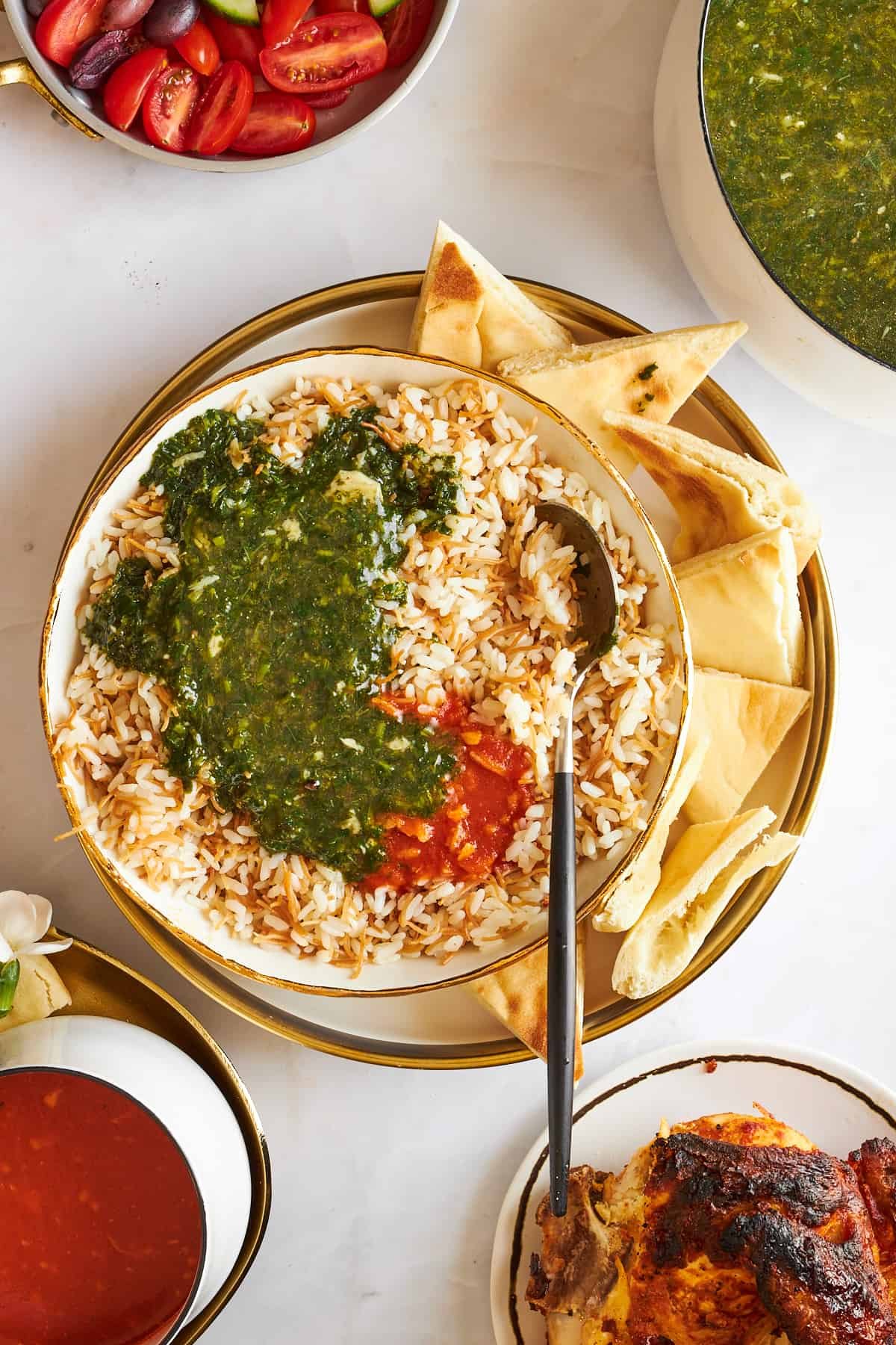 A bowl of vermicelli rice topped with mulukhiya and tomatoes with pita bread on the side.