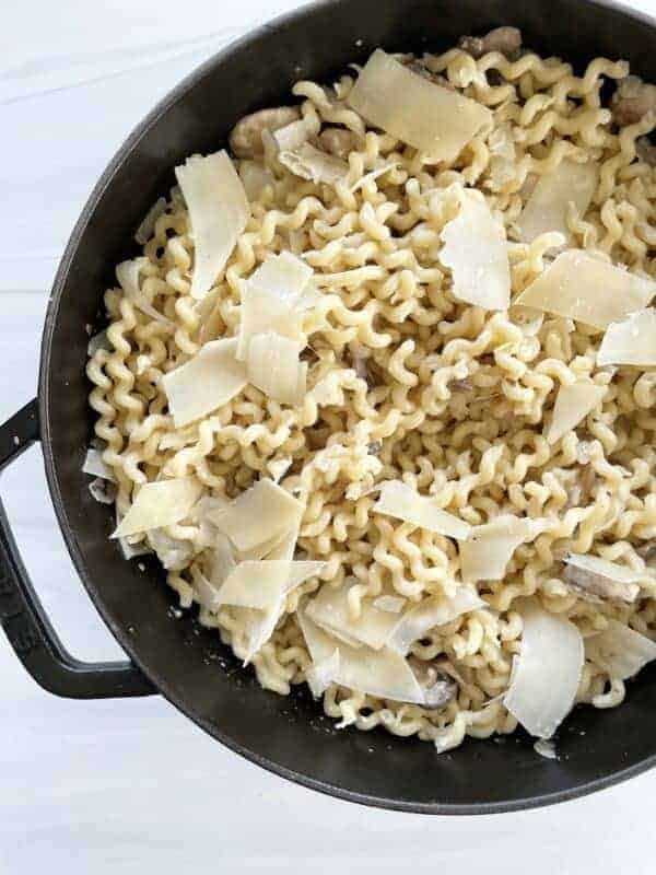 a pot full of mushroom stroganoff with fusilli pasta topped with shaved Parmesan