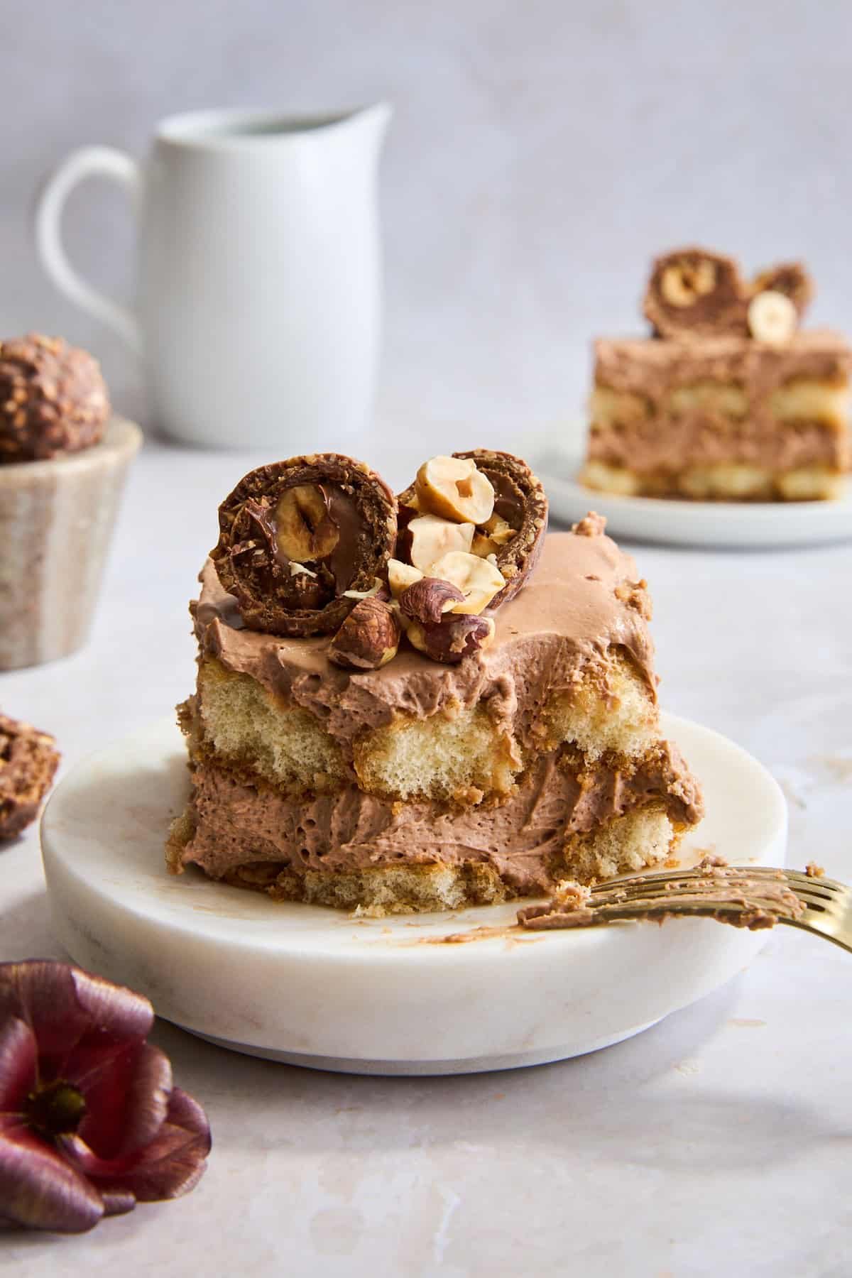 A slice of Nutella tiramisu on a plate with a bite missing and a fork balanced on the edge.