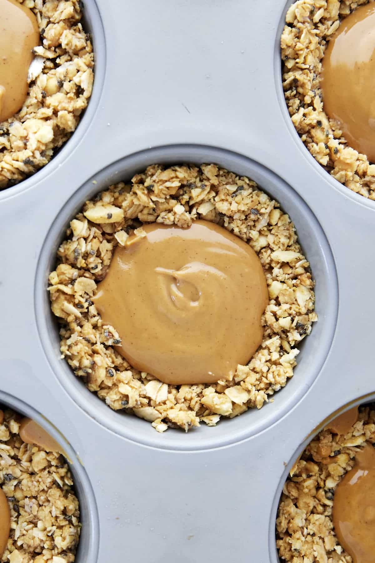 An oat cup in a muffin tin full of peanut butter.