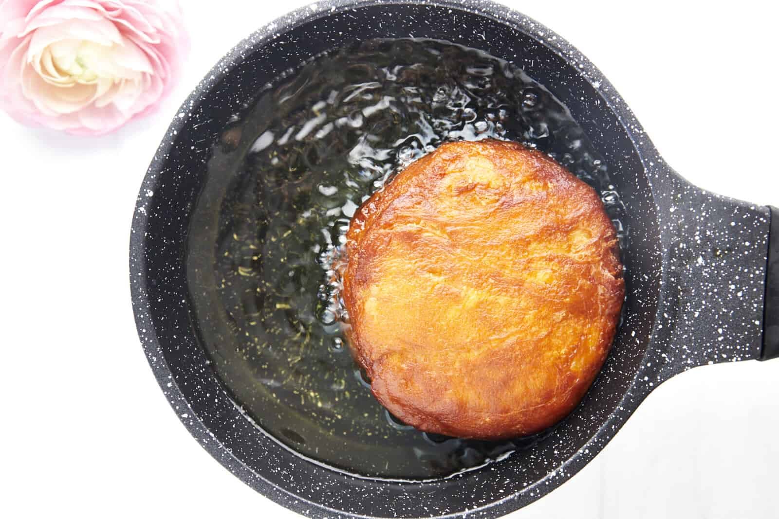 A Nutella stuffed doughscuit frying in oil.