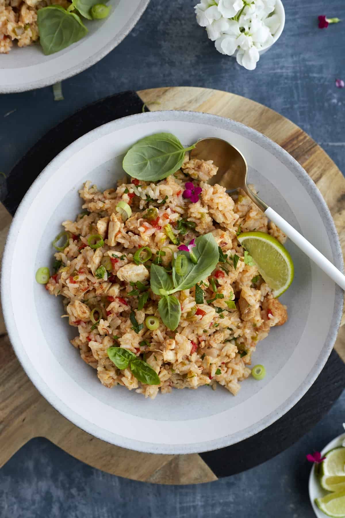 Fajita seasoned rice in a white bowl topped with green onions, fresh herbs, and a lime wedge