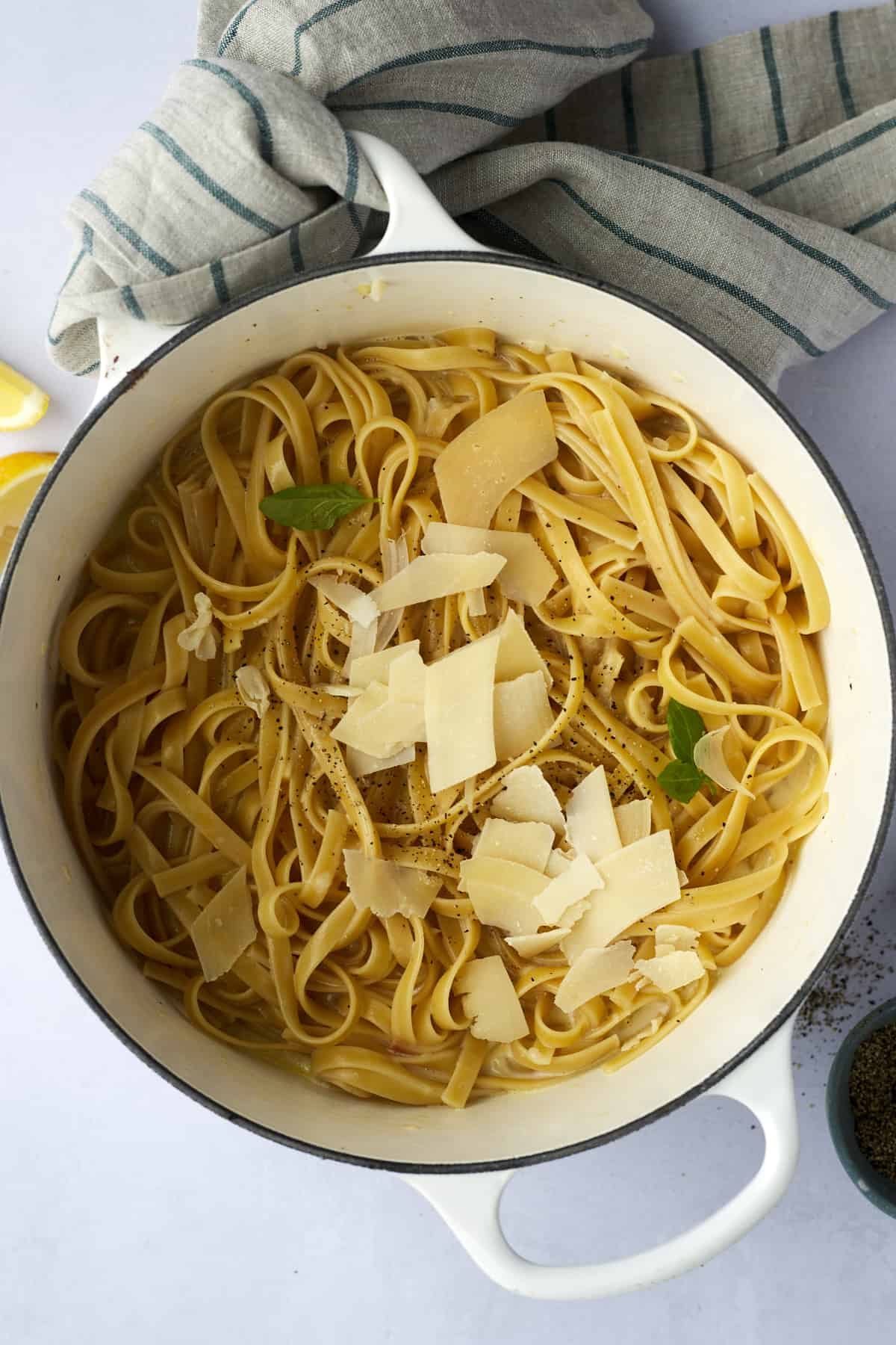 Overhead image of a pot of fettuccine alfredo topped with Parmesan flakes.