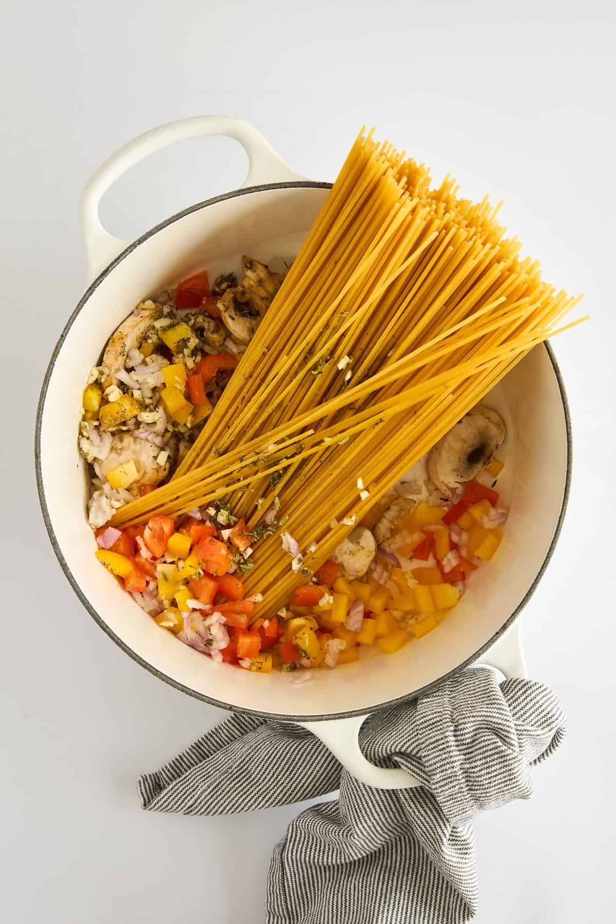 Sautéed veggies and spaghetti in a pot.