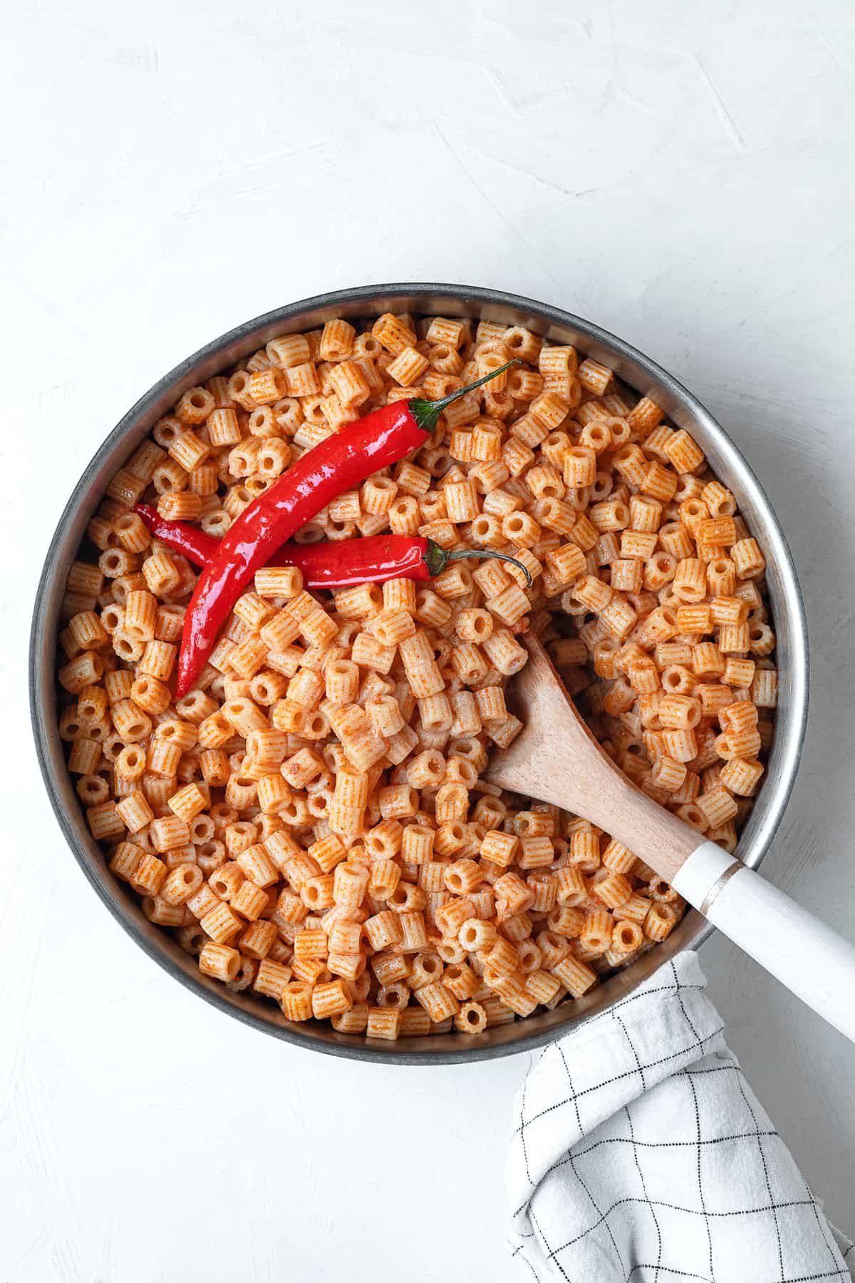 overhead image of one pot mbakbaka topped with peppers being stirred with a spoon