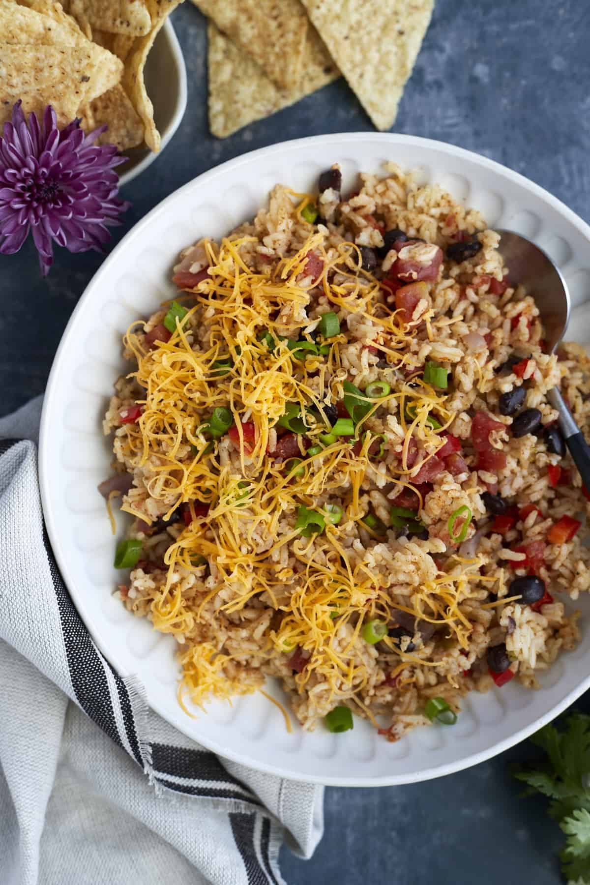 Overhead image of a white plate full of simple Mexican rice with cheese and veggies
