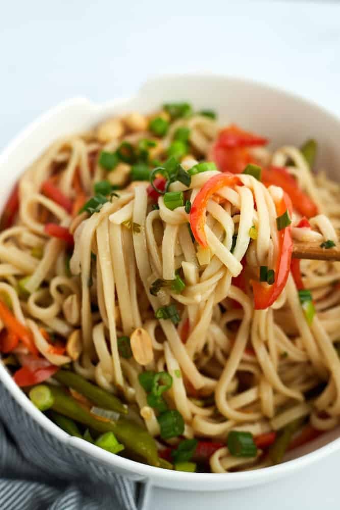 chopsticks scooping up a bite of vegetarian ramen from a bowl.