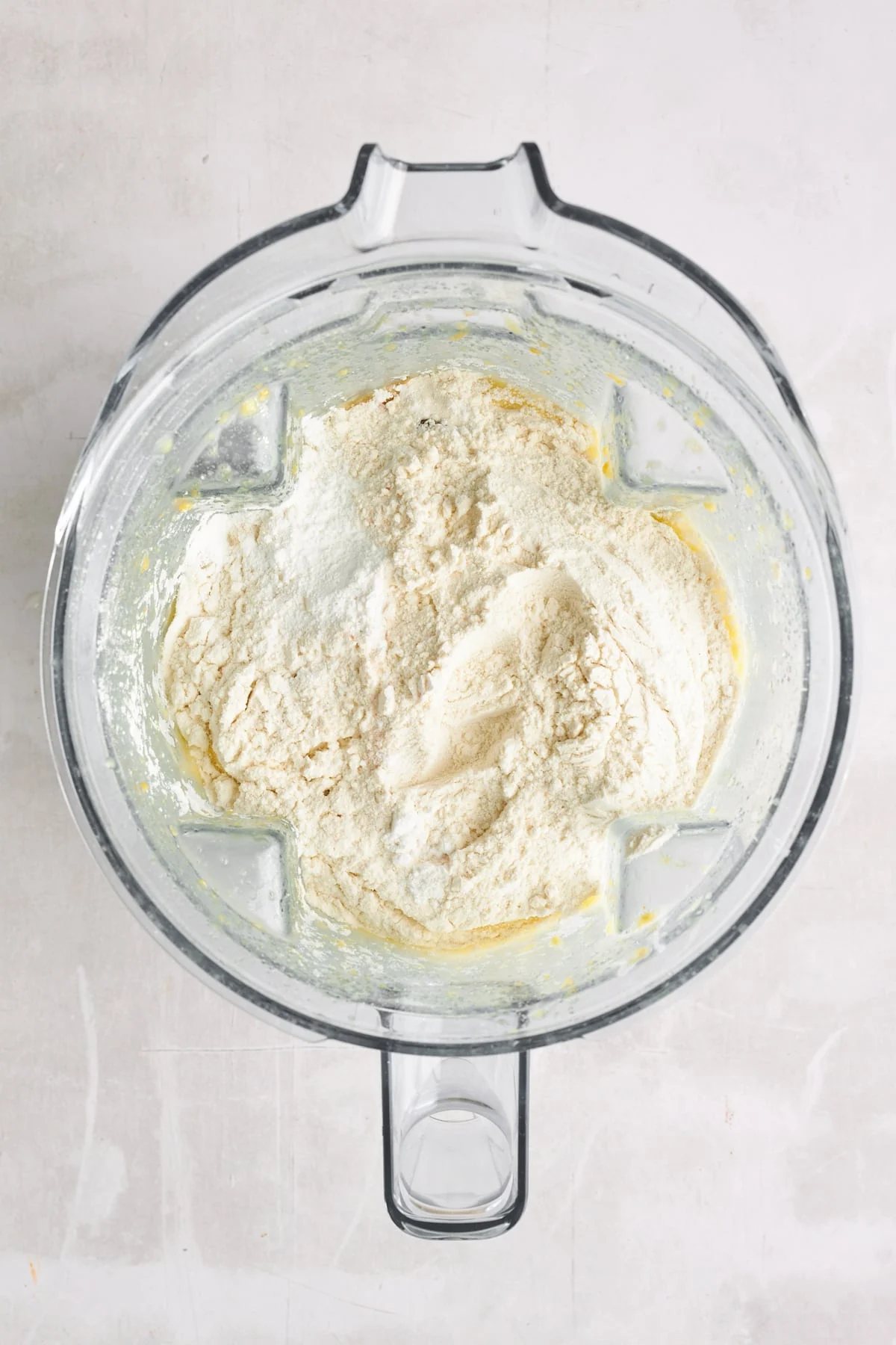 Dry ingredients being added to wet ingredients in a blender.