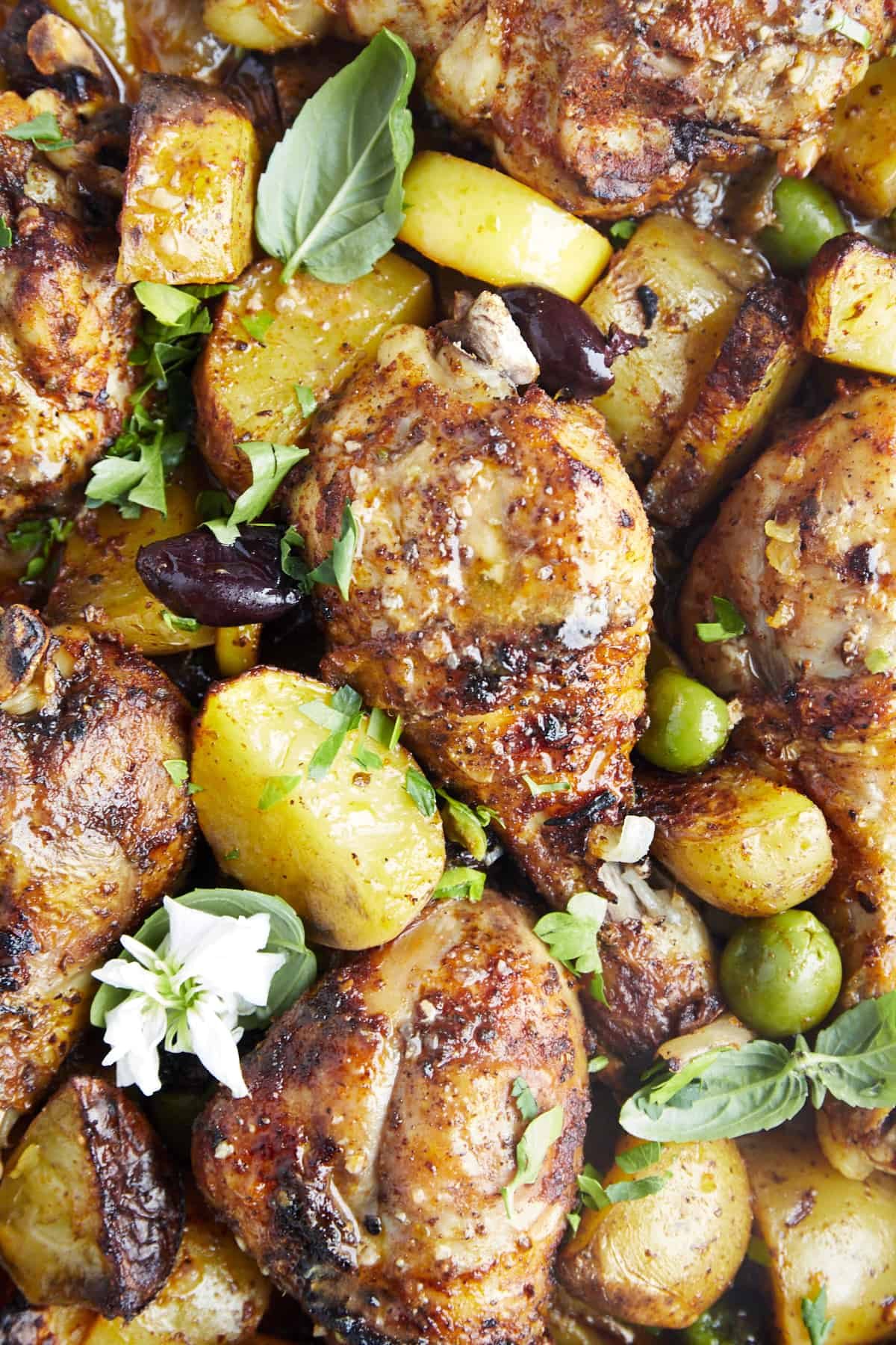Oven baked chicken drumsticks with potatoes and olives.