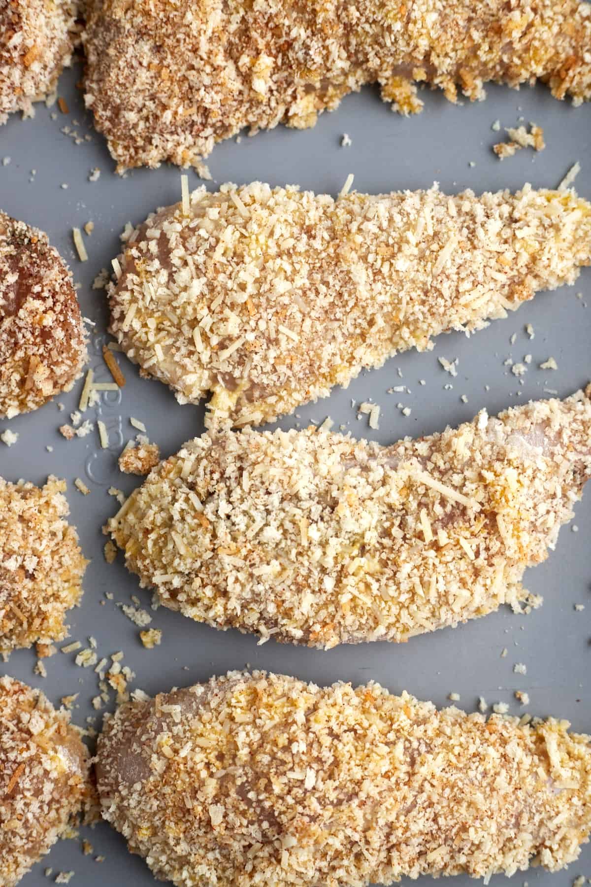 raw panko breaded chicken tenders on a baking sheet
