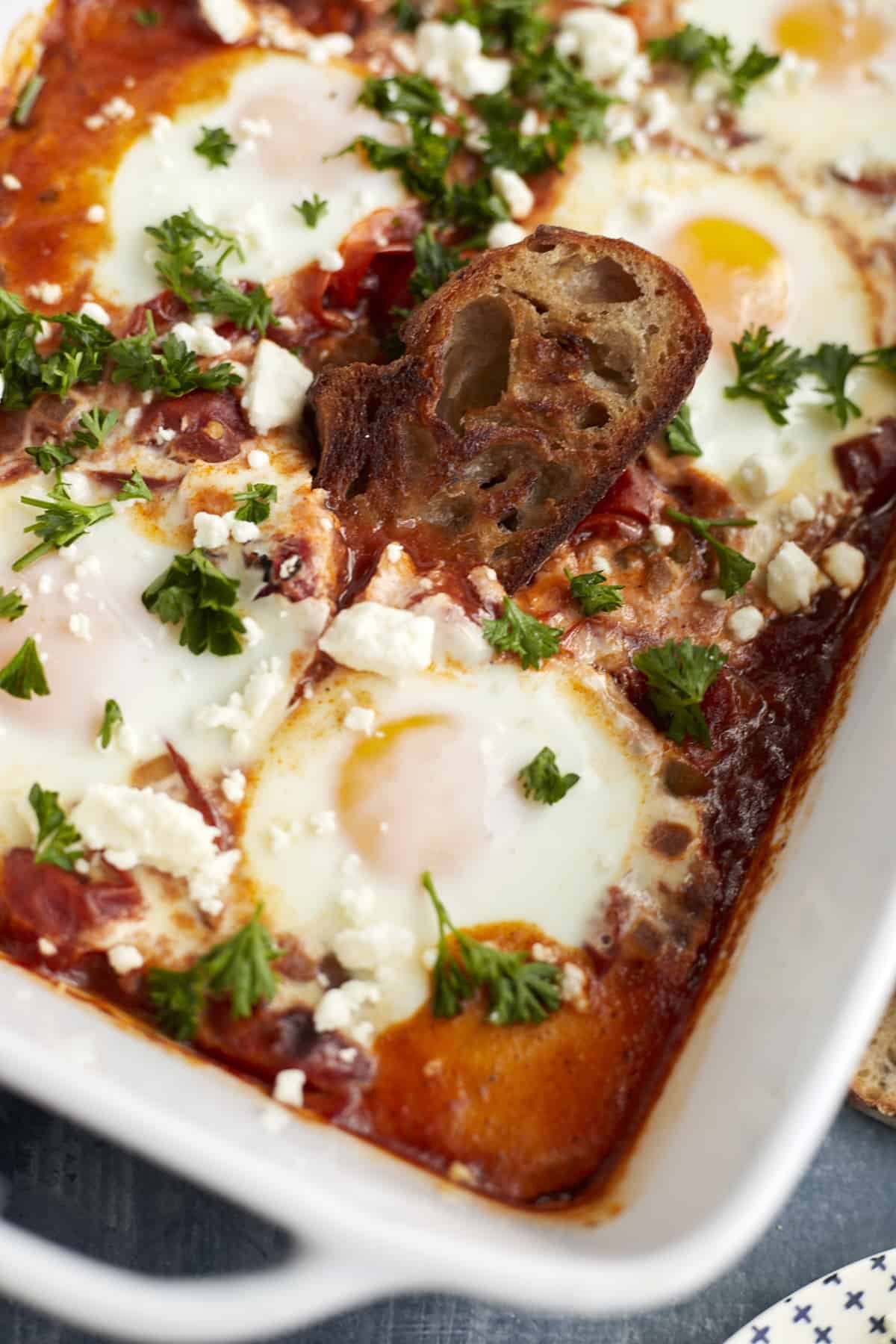 a piece of toasted bread dipping into oven baked shakshuka