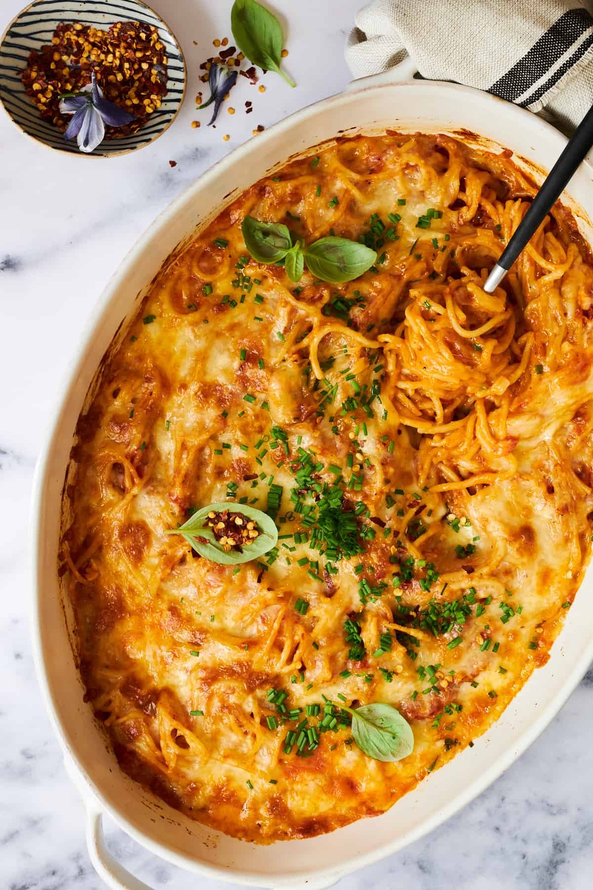 An oval baking dish of oven baked spaghetti.
