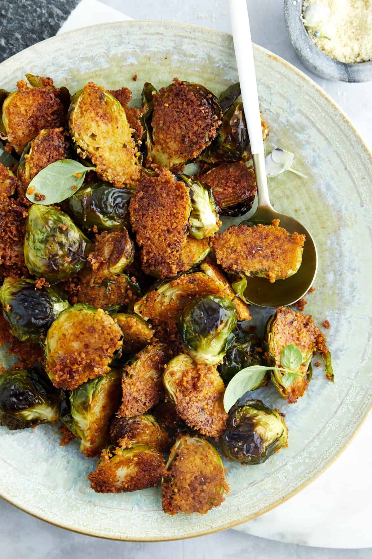 A spoon scooping up an Oven Roasted Parmesan Brussel Sprout from a plate.