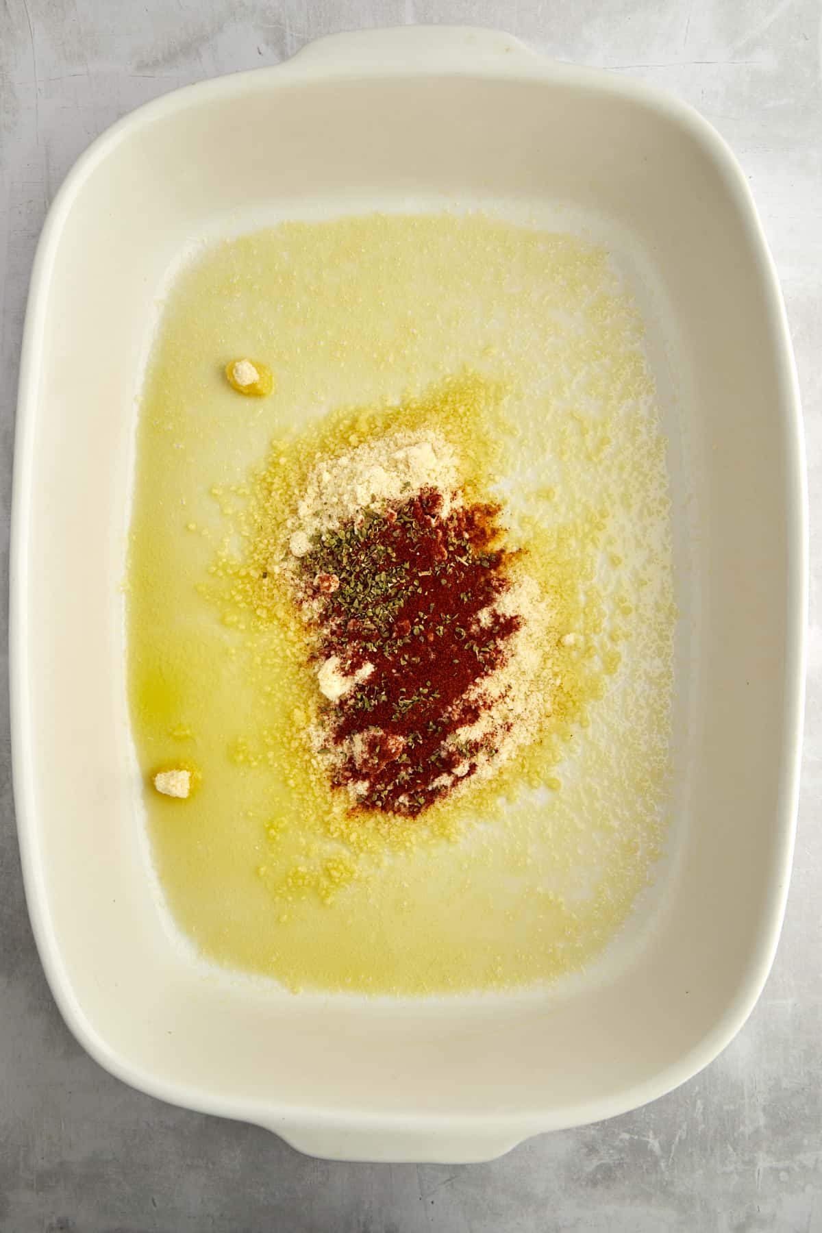 A baking dish with butter and spices in the bottom.