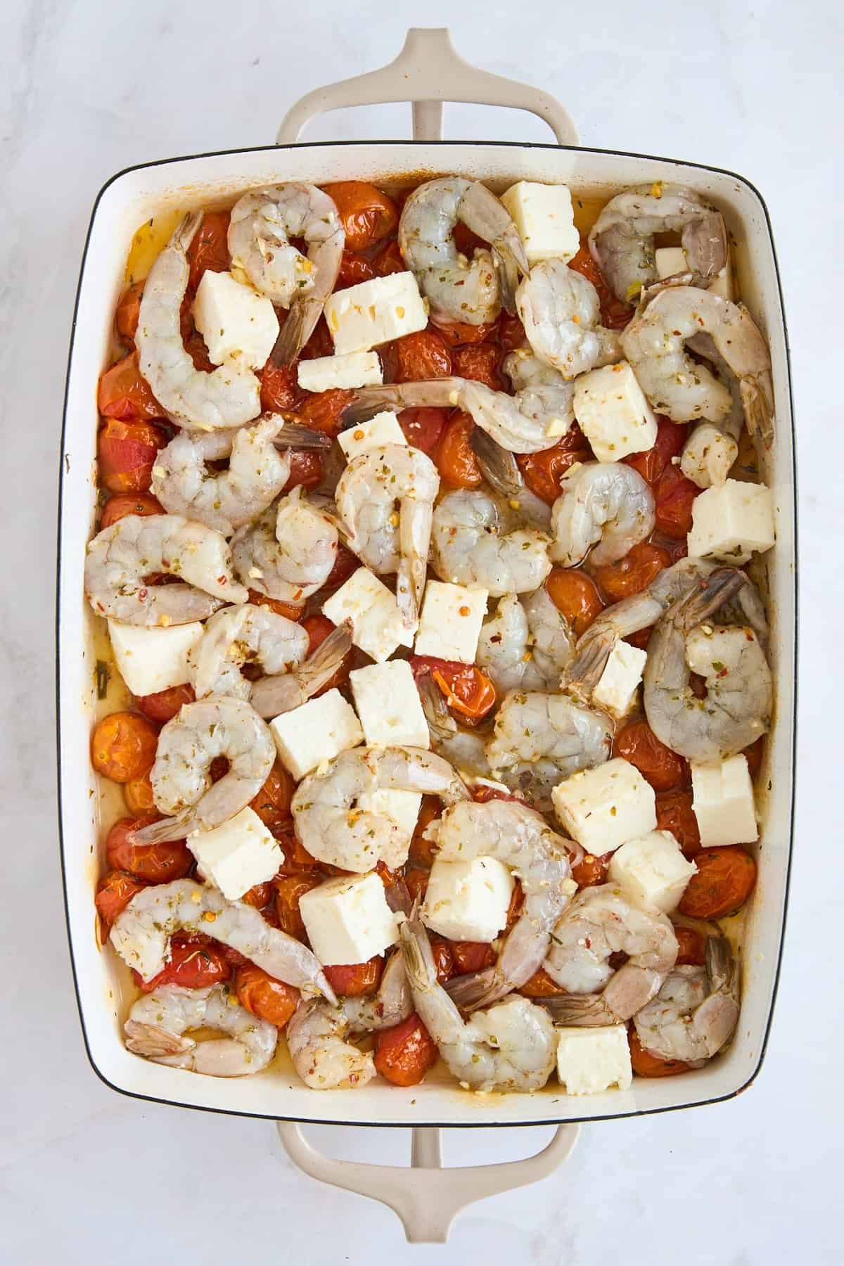 Baked tomatoes topped with feta cubes and raw shrimp.