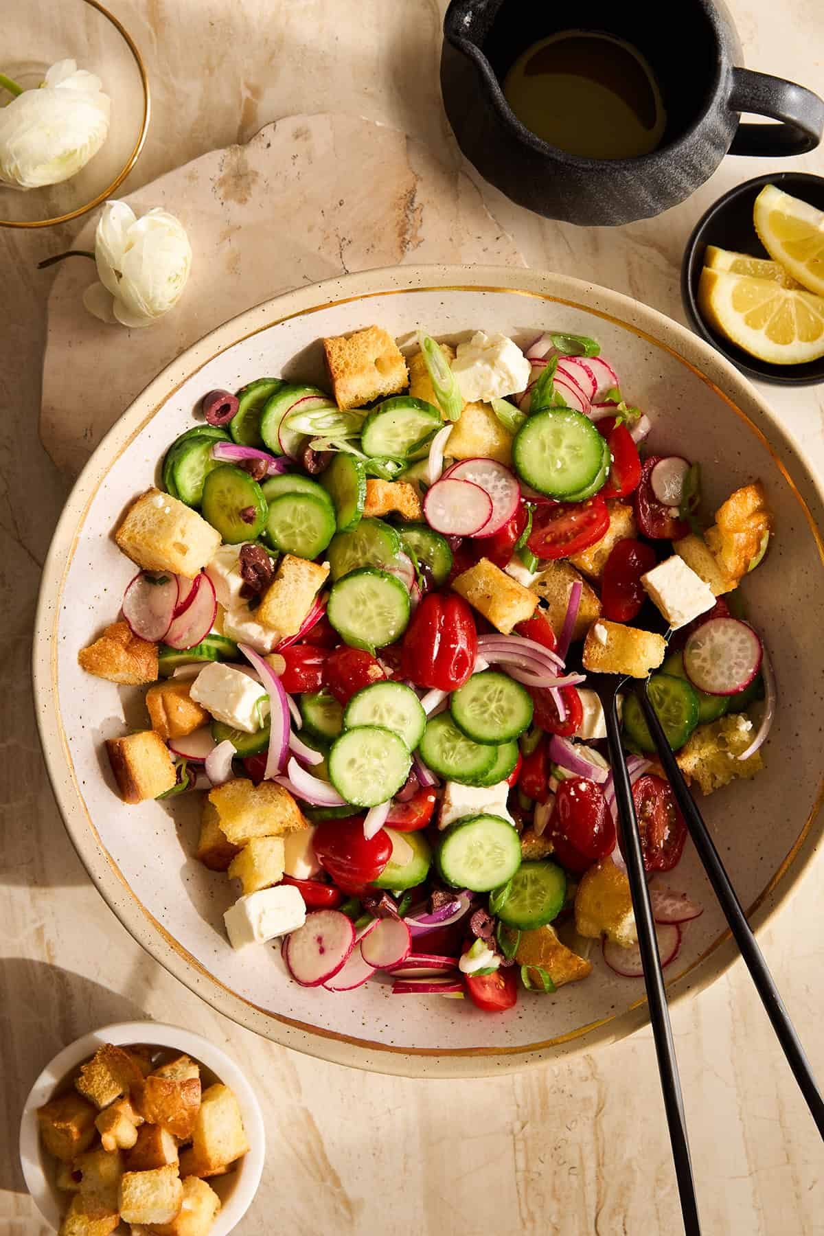 Panzanella salad in a bowl with two serving spoons sticking out.