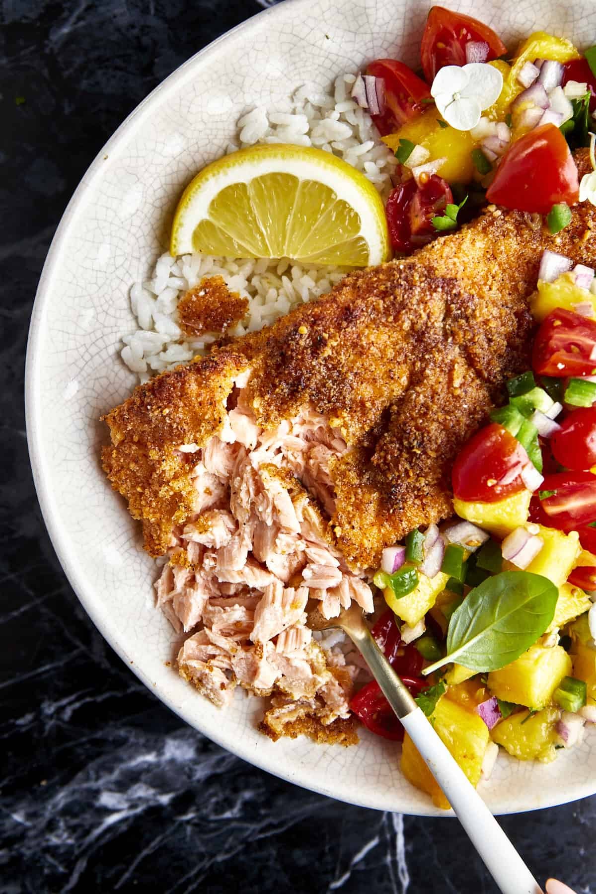 Flaked Parmesan crusted salmon with mango salsa in a bowl over white rice.
