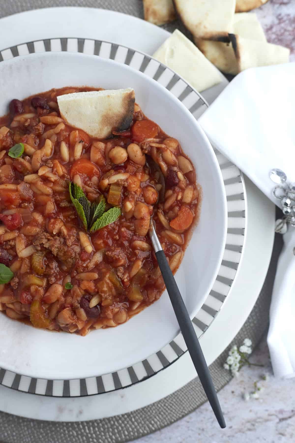 a bowl of soup with a spoon dipped in and bread on the side