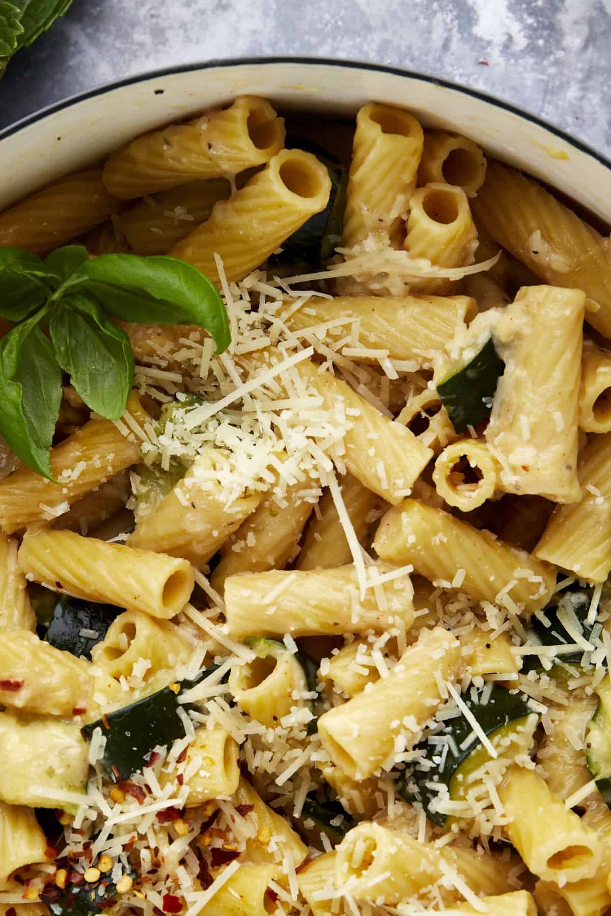 Close up image of cooked pasta with zucchini topped with Parmesan cheese.