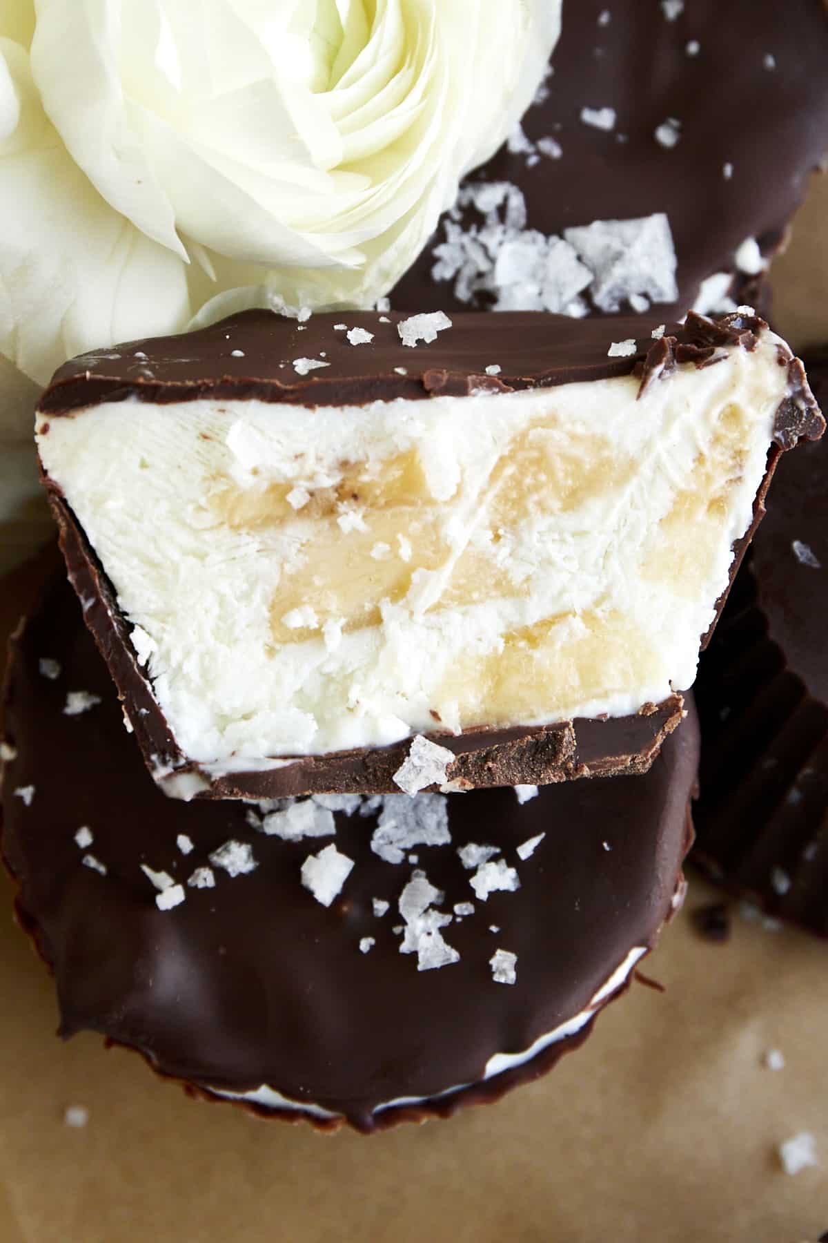 Close up image of half a peanut butter banana chocolate covered frozen yogurt bite topped with sea salt.