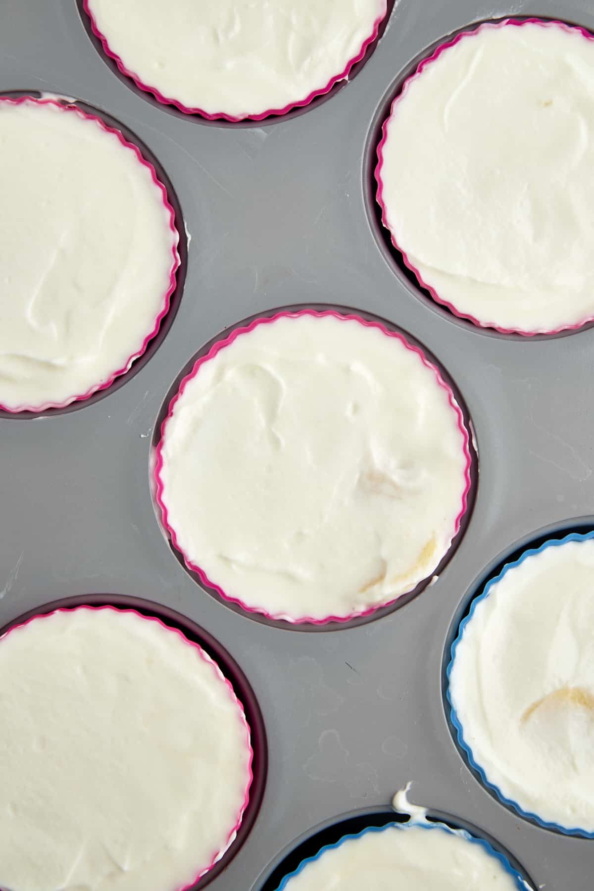 Overhead image of a yogurt, banana, and honey mixture in a silicone-lined mini muffin tin.